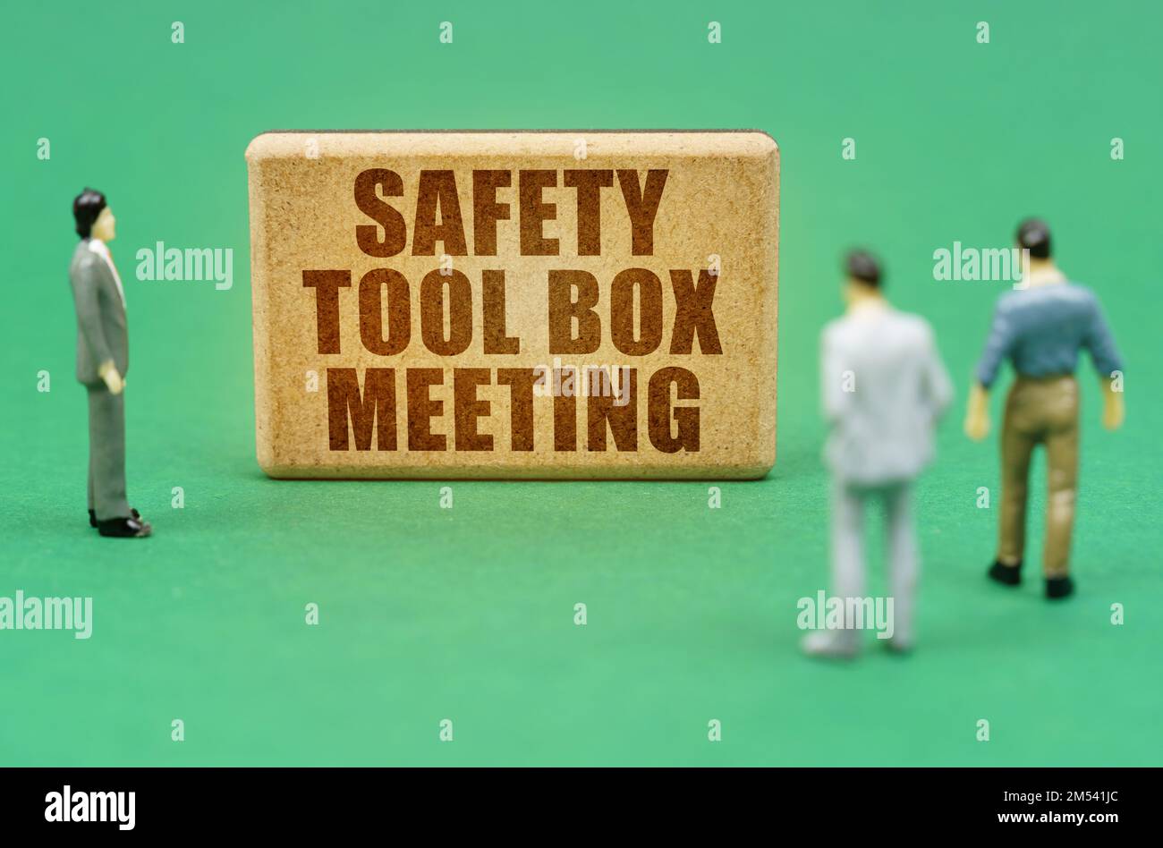 Security and insurance concept. On the green surface are figures of people and a sign with the inscription - Safety Tool box Meeting Stock Photo