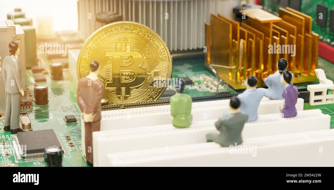 Business and technology concept. On the motherboard of the computer is a gold bitcoin coin and miniature figures of people. Figures out of focus. Bann Stock Photo