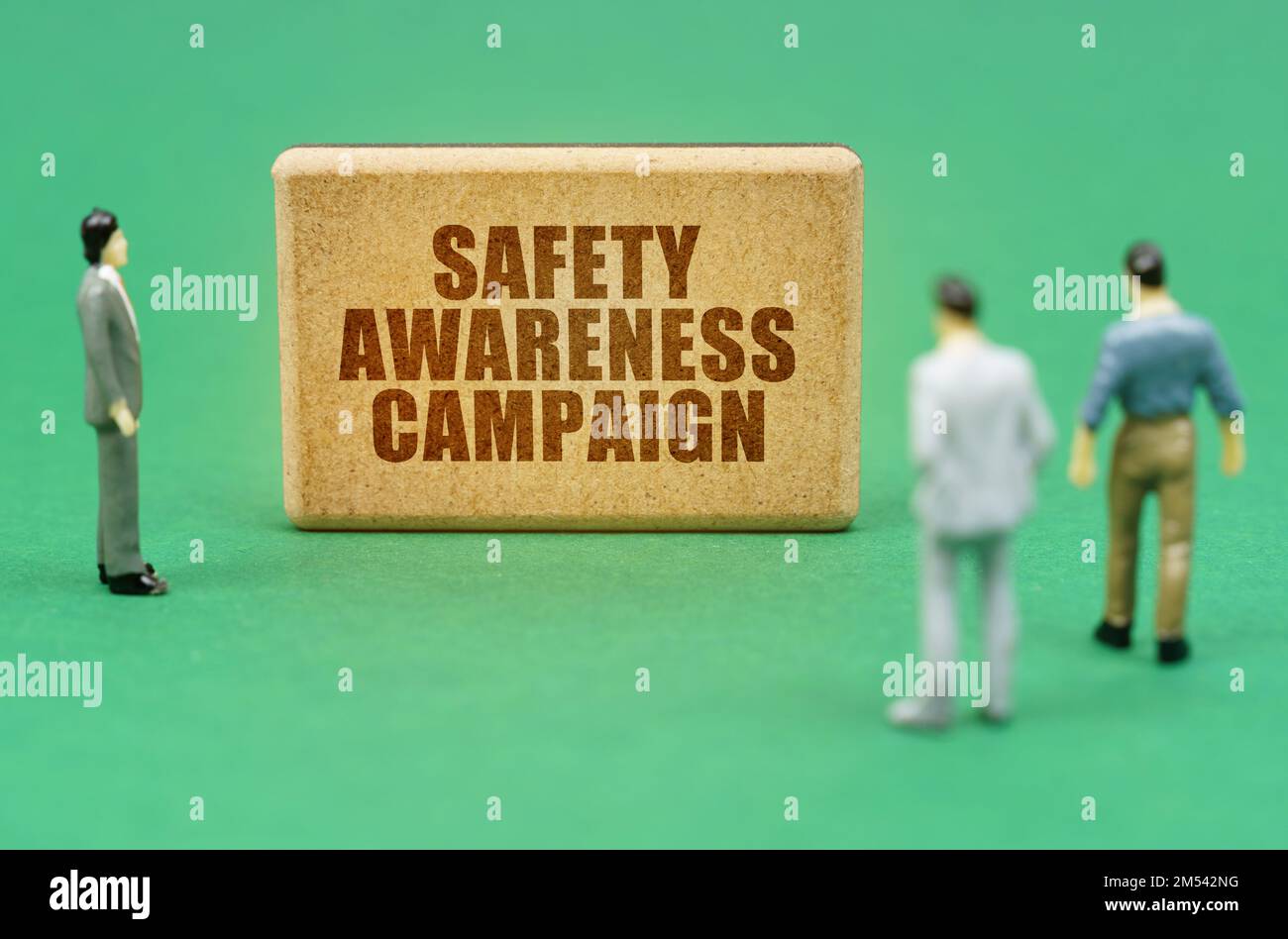 Security and insurance concept. On the green surface are figures of people and a sign with the inscription - Safety Awareness Campaign Stock Photo