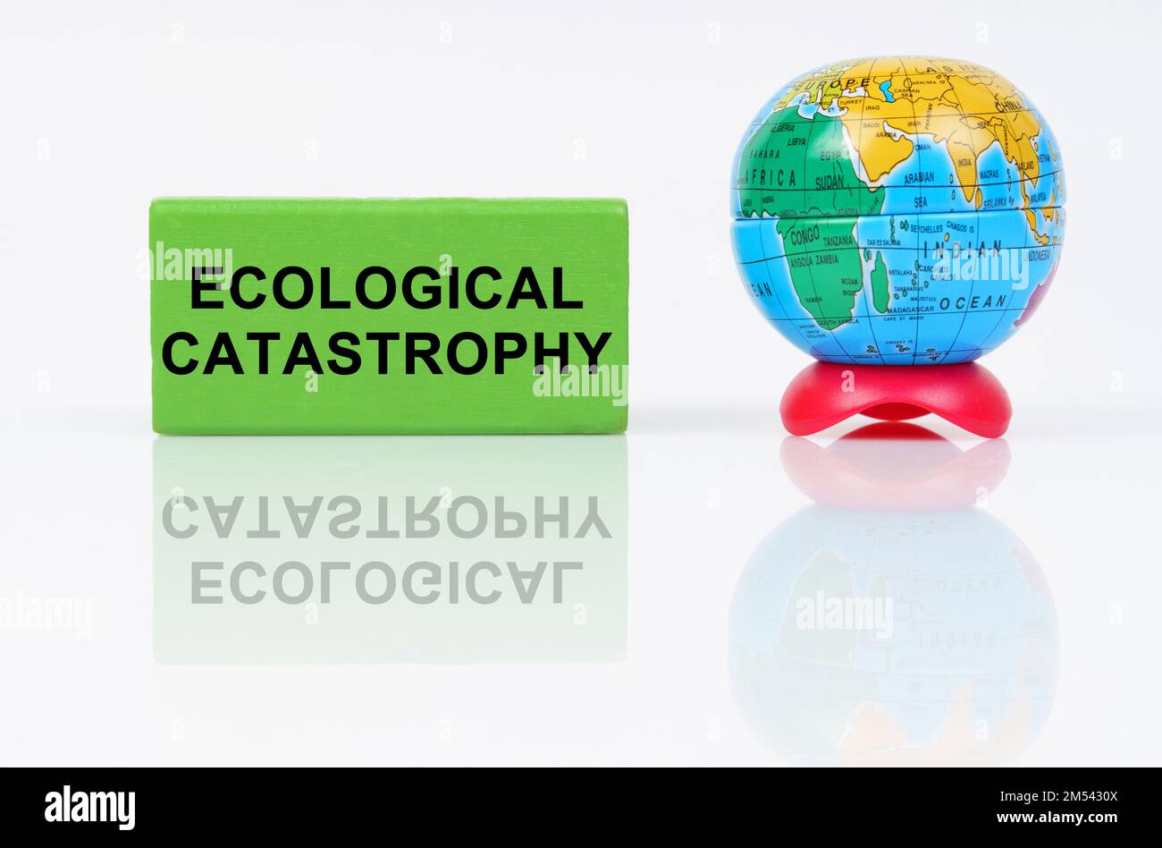 Ecological concept. On a reflective surface is a globe and a green sign with the inscription - Ecological catastrophy Stock Photo