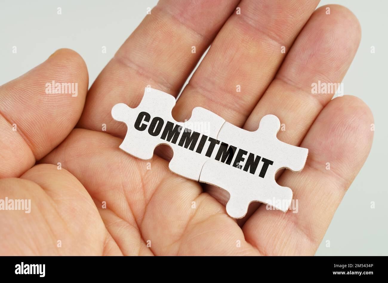 Business concept. In the hand of a man are puzzles with the inscription - COMMITMENT Stock Photo