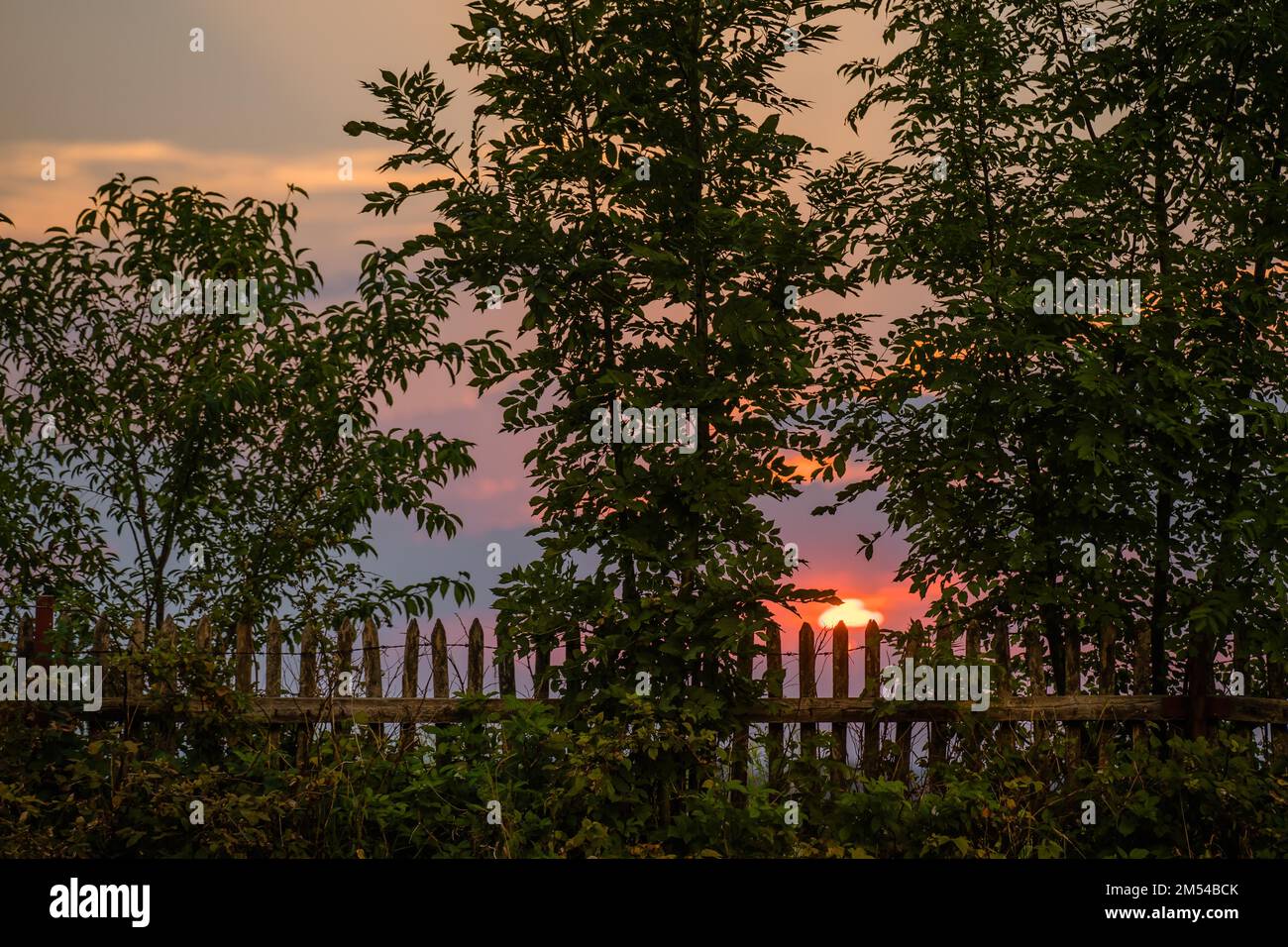 Rural wooden fence against the backdrop of the setting sun, dolnoÅ›laskie, Poland Stock Photo