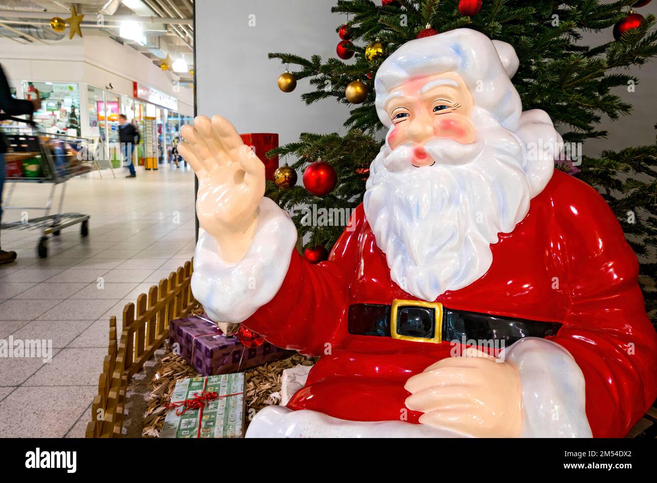 Father Christmas waving to passersby with shopping trolley, Father