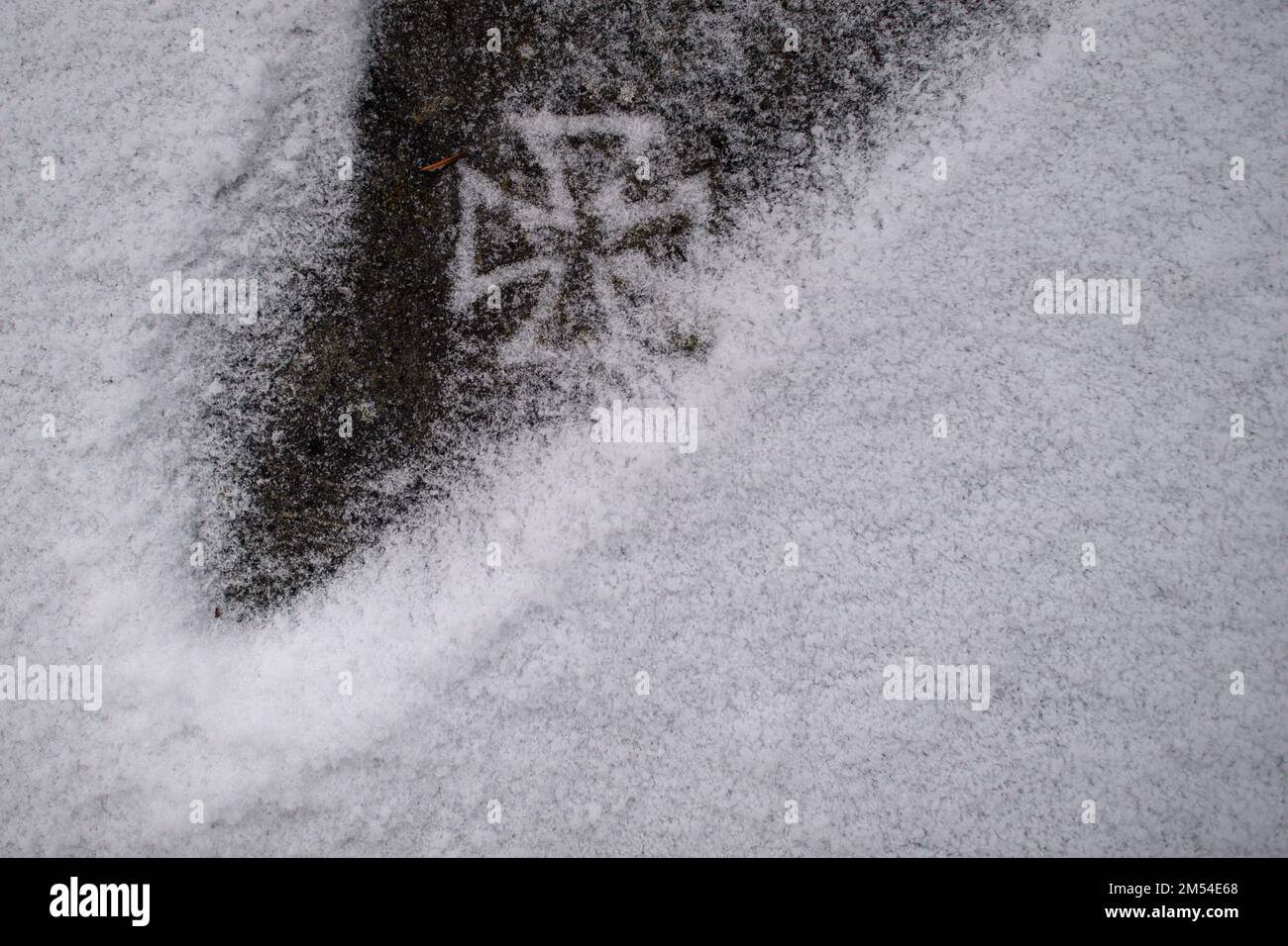 PRODUCTION - 14 December 2022, Saxony-Anhalt, Schönebeck: An iron cross can be seen under snow on a weathered memorial plaque for World War 1 fallen. Photo: Klaus-Dietmar Gabbert/dpa Stock Photo