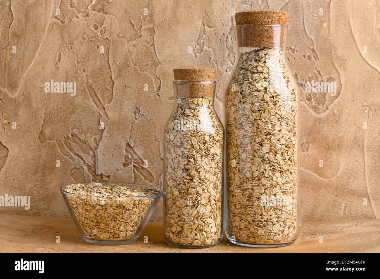 Bottles and bowl of raw oatmeal on color table Stock Photo Alamy