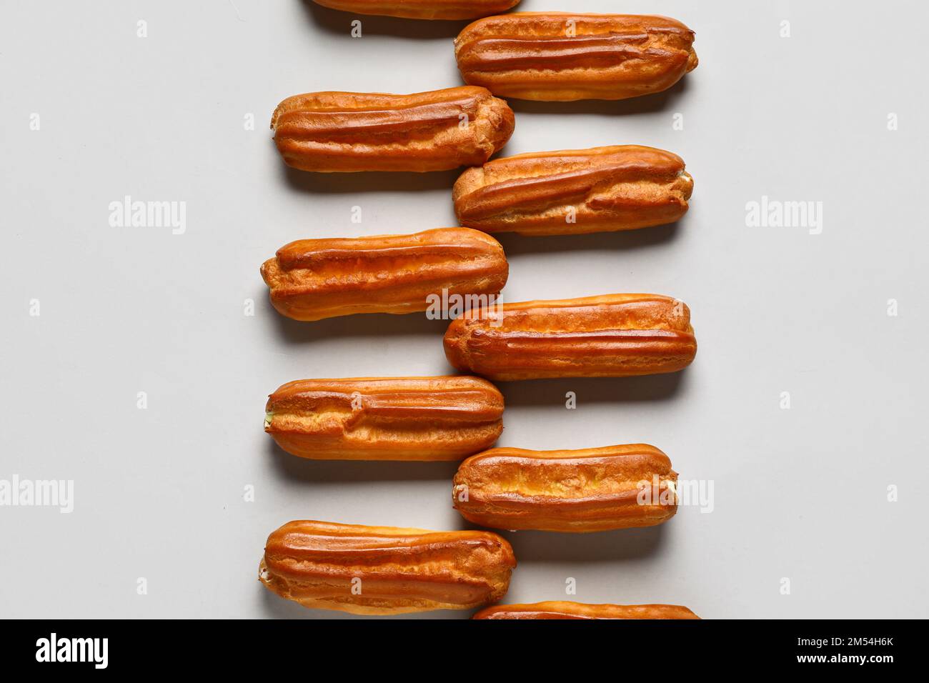 Composition with sweet eclairs on light background Stock Photo