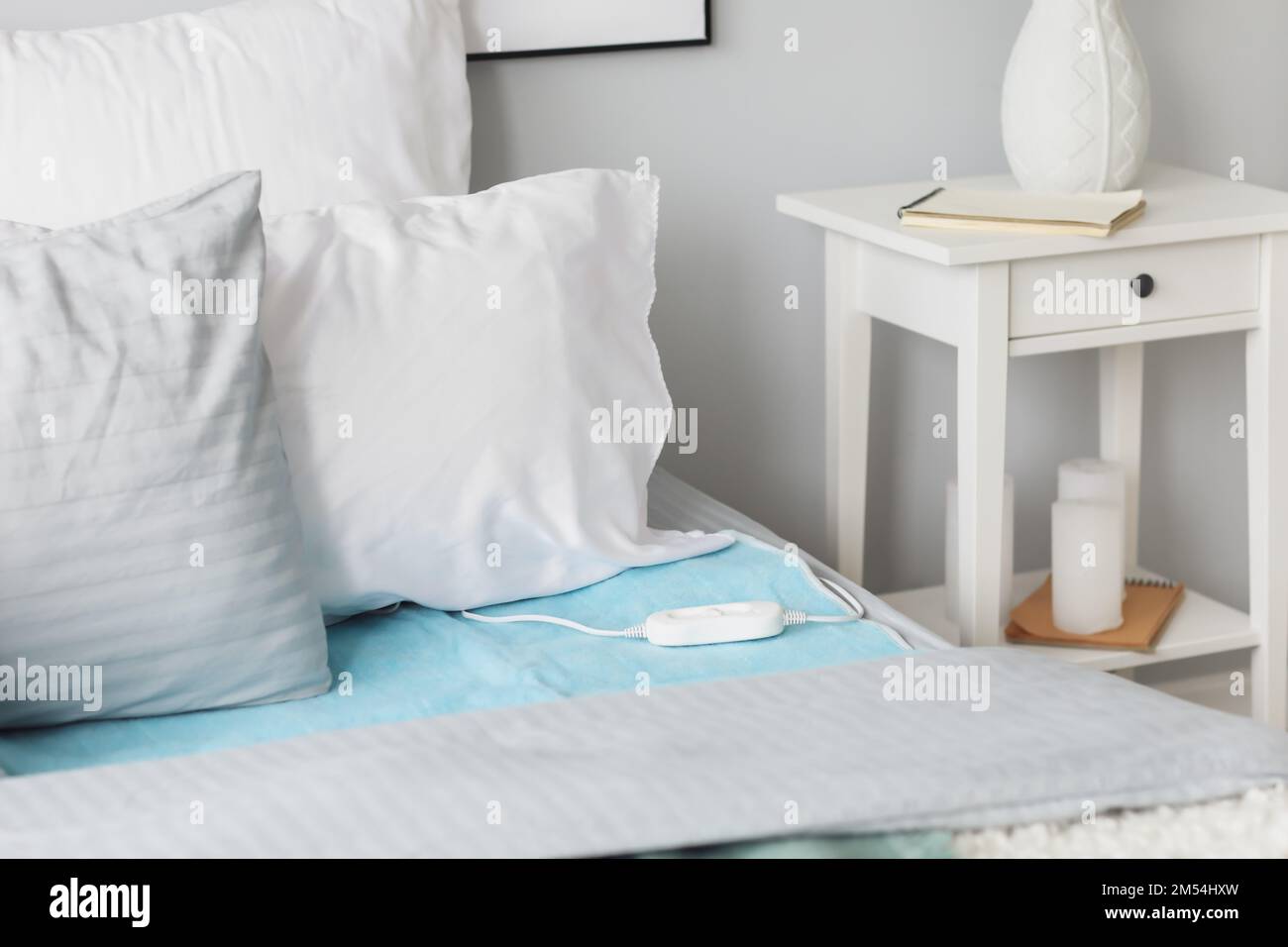 Bed with electric heating pad in bedroom Stock Photo