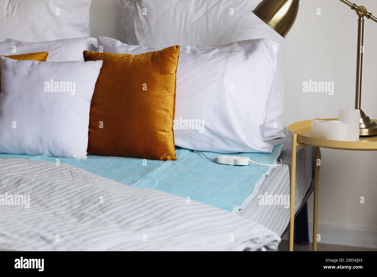 Bed with electric heating pad in bedroom Stock Photo