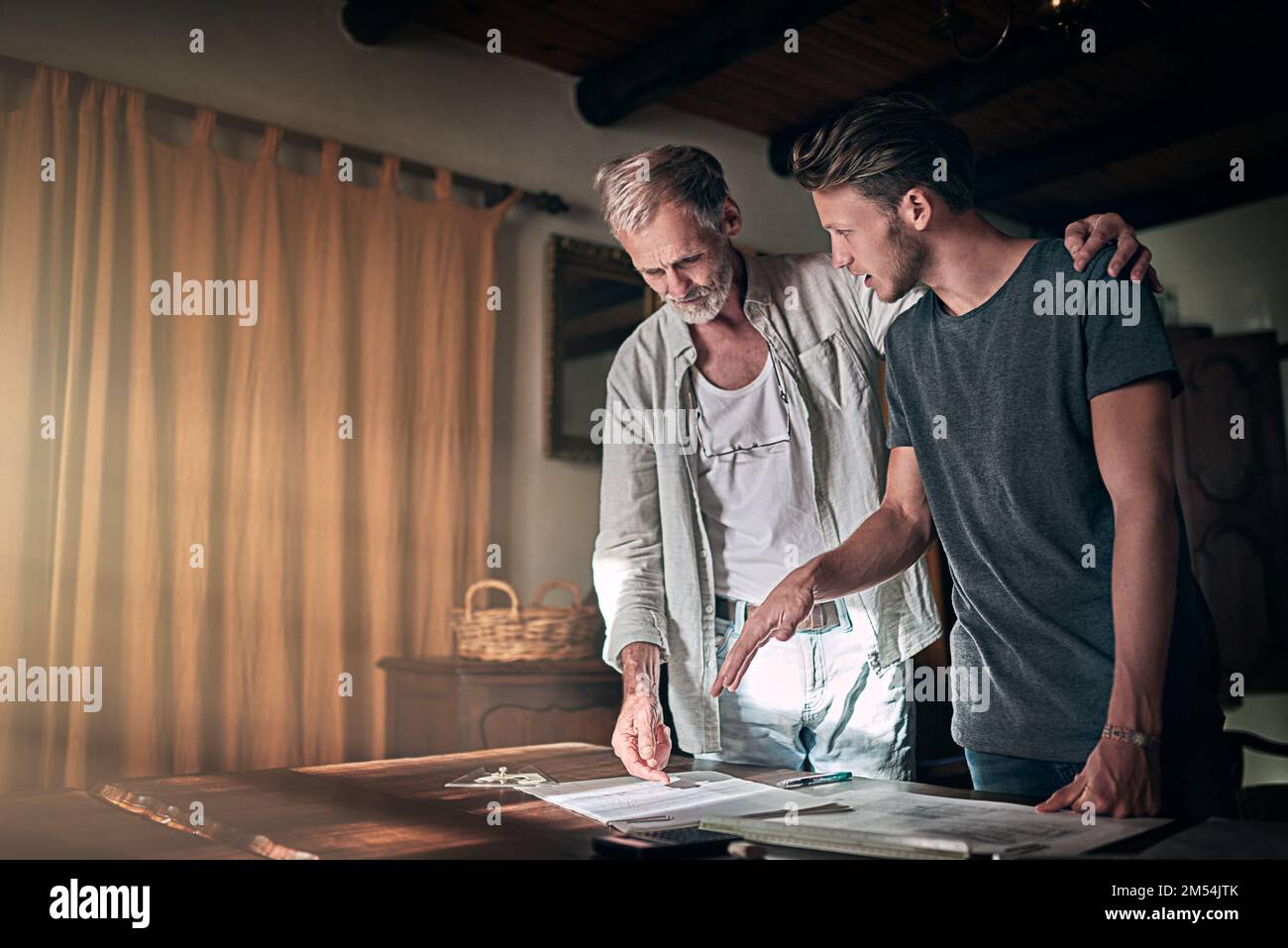 Getting advice from an old pro. a father and his son working on a design for their family business at home. Stock Photo