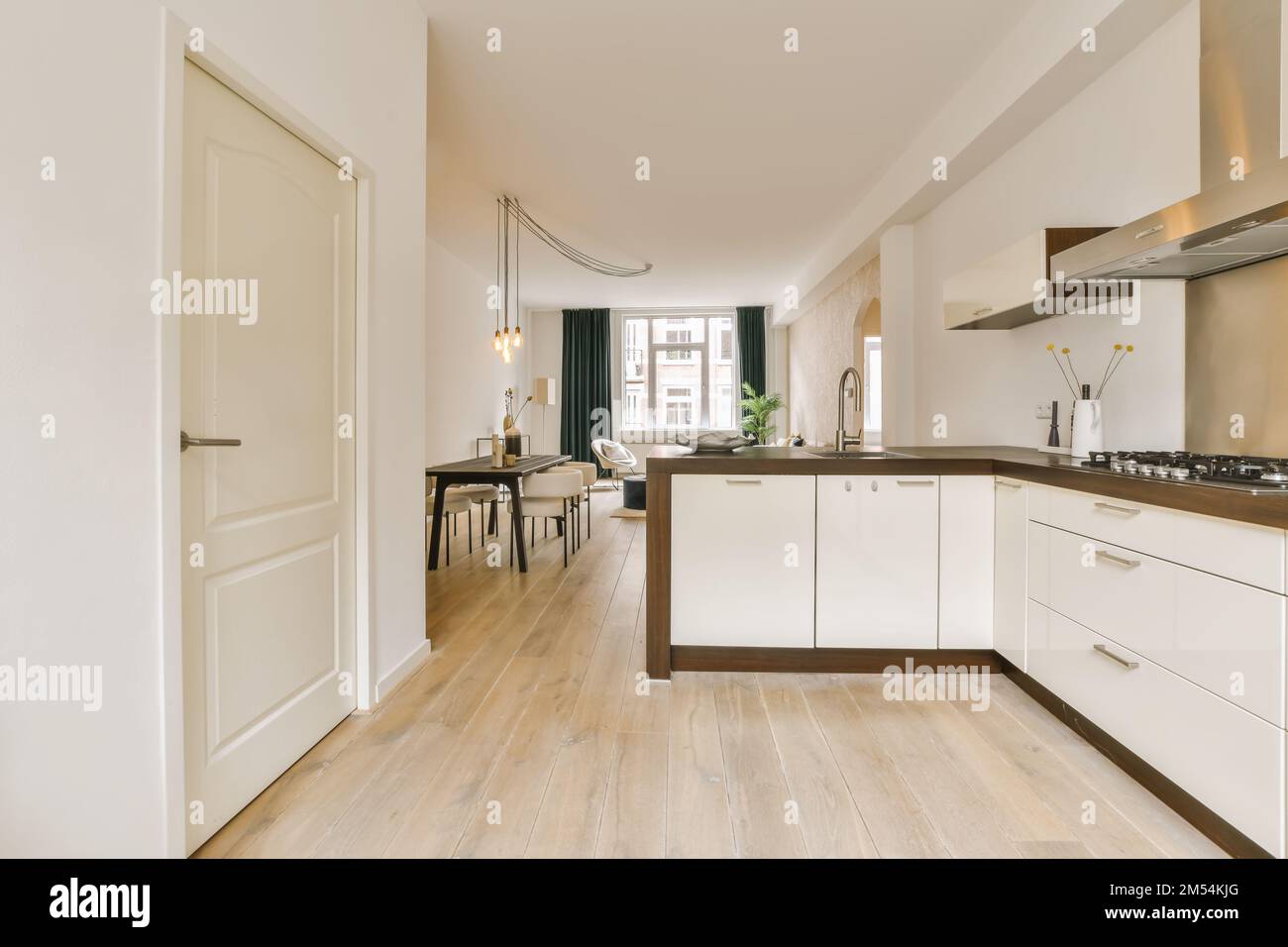 a kitchen and dining area in a house with wood flooring, white cabinets and counters on either sides Stock Photo