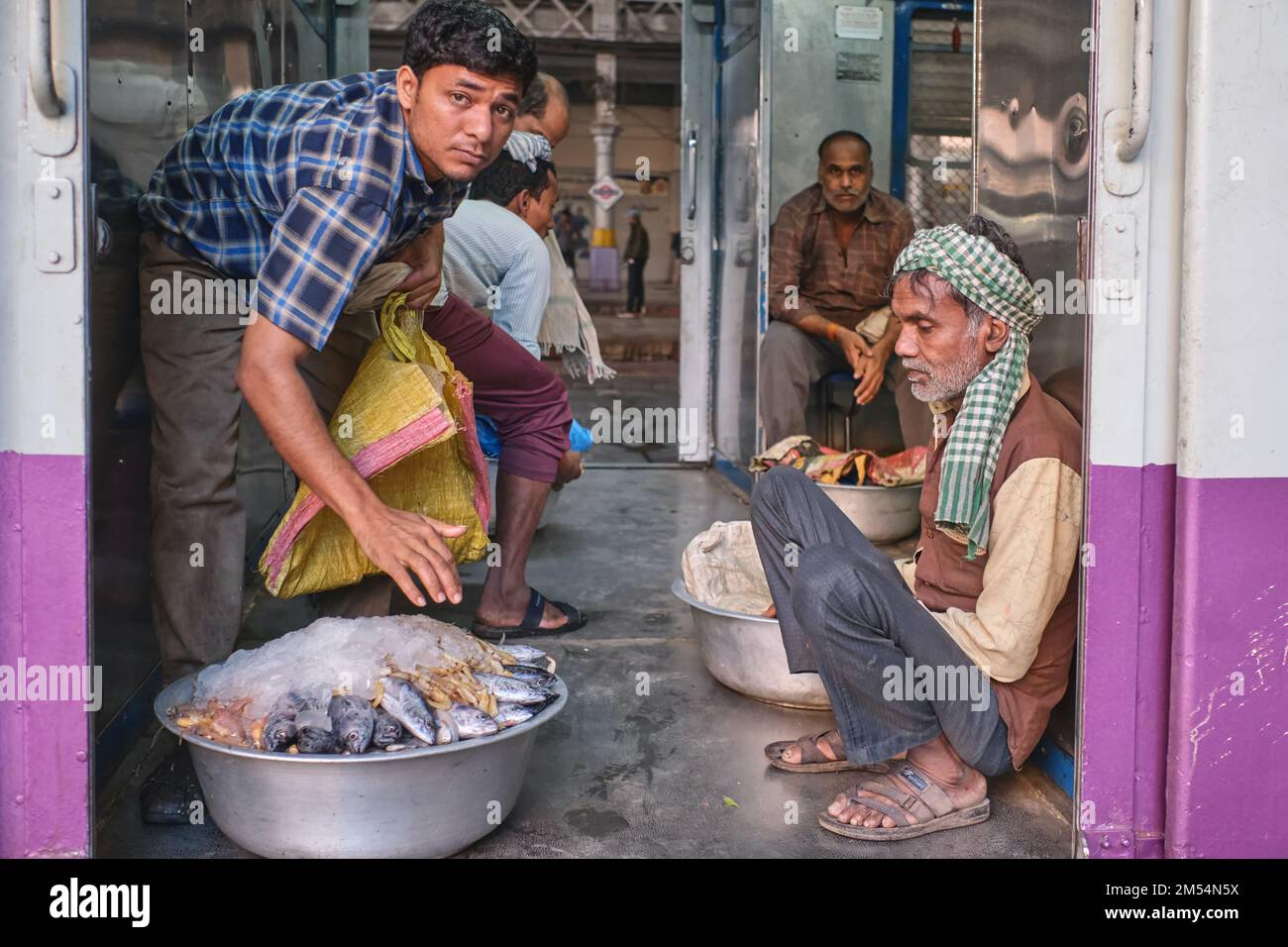 Porters with trays of fish sitting in the luggage compartment of a local train at Chhatrapati Shivaji Maharaj Terminus (CSMT) in Mumbai, India Stock Photo