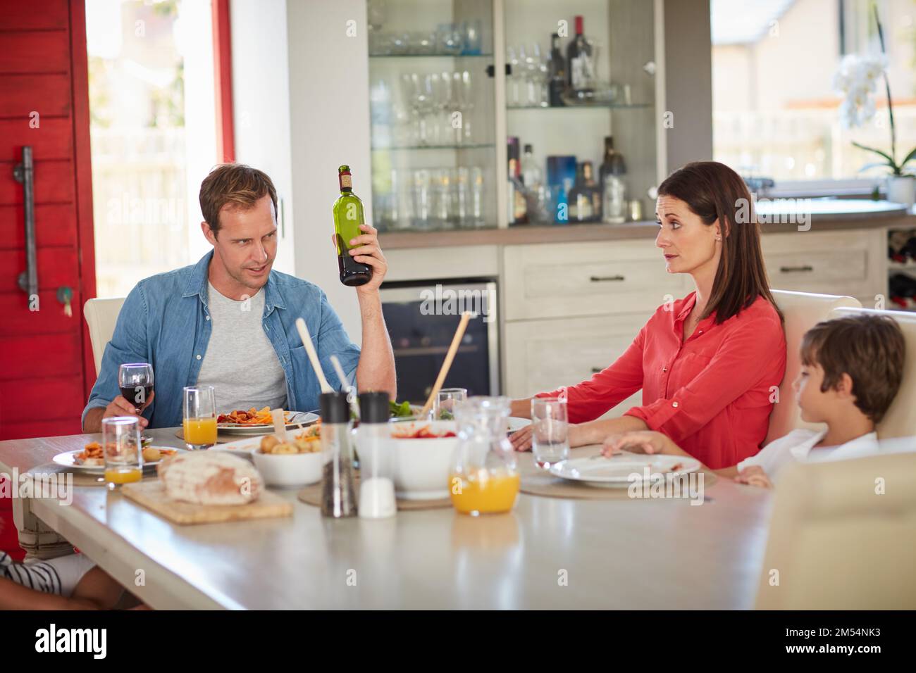 Havent you had enough wine, dear. a drunk man and his wife arguing in front of their children during lunch. Stock Photo