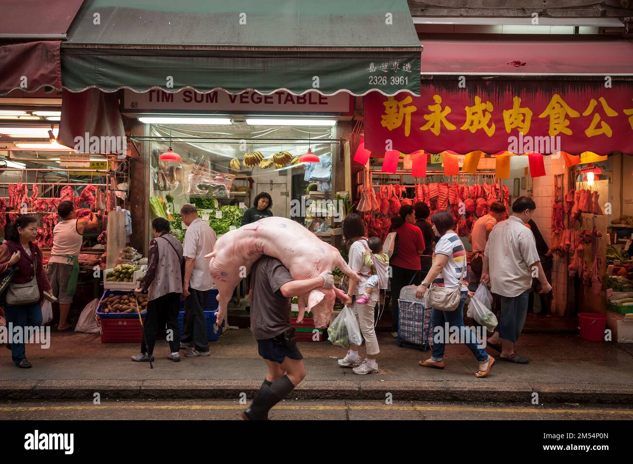 A worker delivers a pig carcass to a butcher in Wan Chai Market, Hong Kong Island Stock Photo