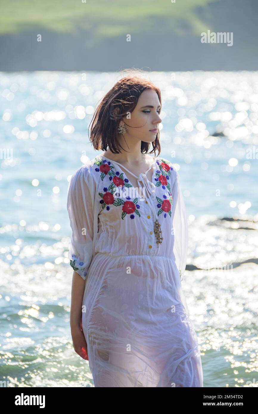 Young woman in white dress walking along the beach Stock Photo - Alamy