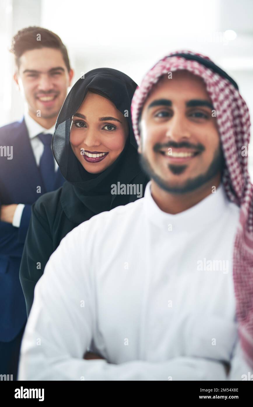 Every member of our team is crucial to success. Portrait of a team of muslim colleagues standing together in a line at the office. Stock Photo