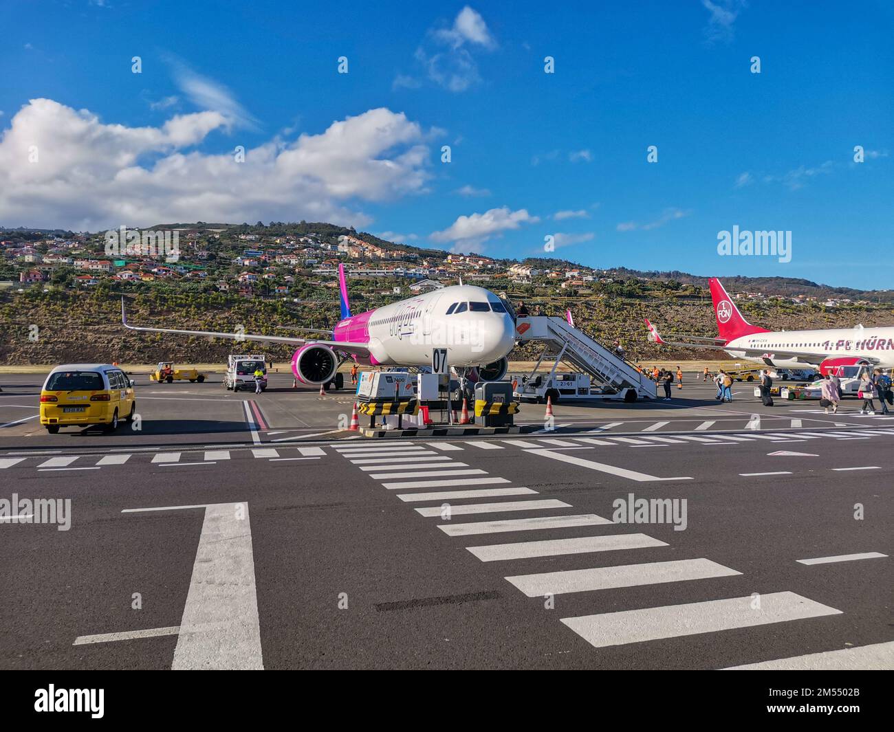 Airplanes at Funchal Airport, Madeira Island, Portugal. Boarding passengers on flight. Plane on background of mountains and houses. Runway strip Stock Photo