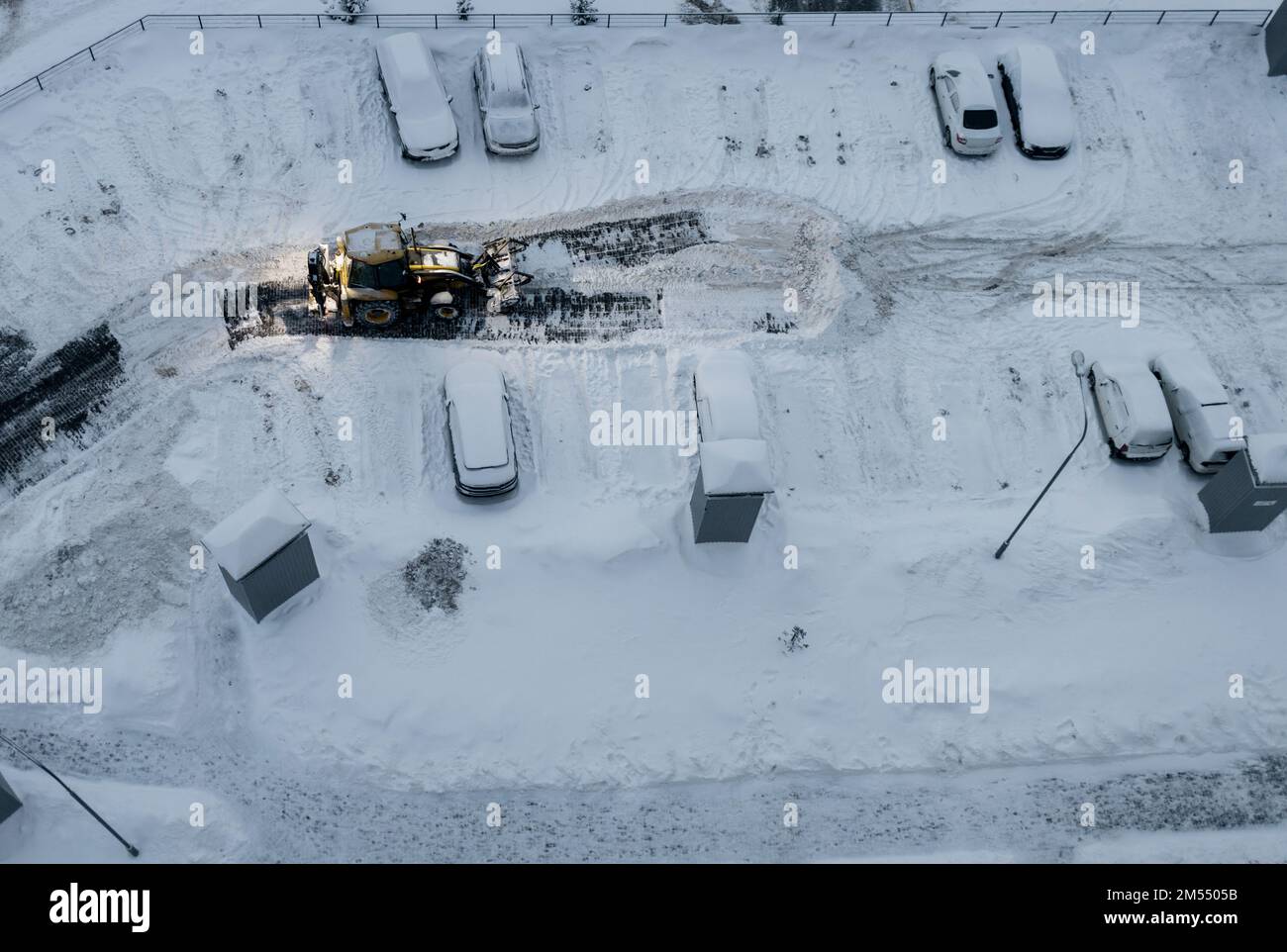 Tractor loader machine uploading dirty snow into dump truck. Cleaning city street, removing snow and ice after heavy snowfalls. Snowplow clean pavemen Stock Photo