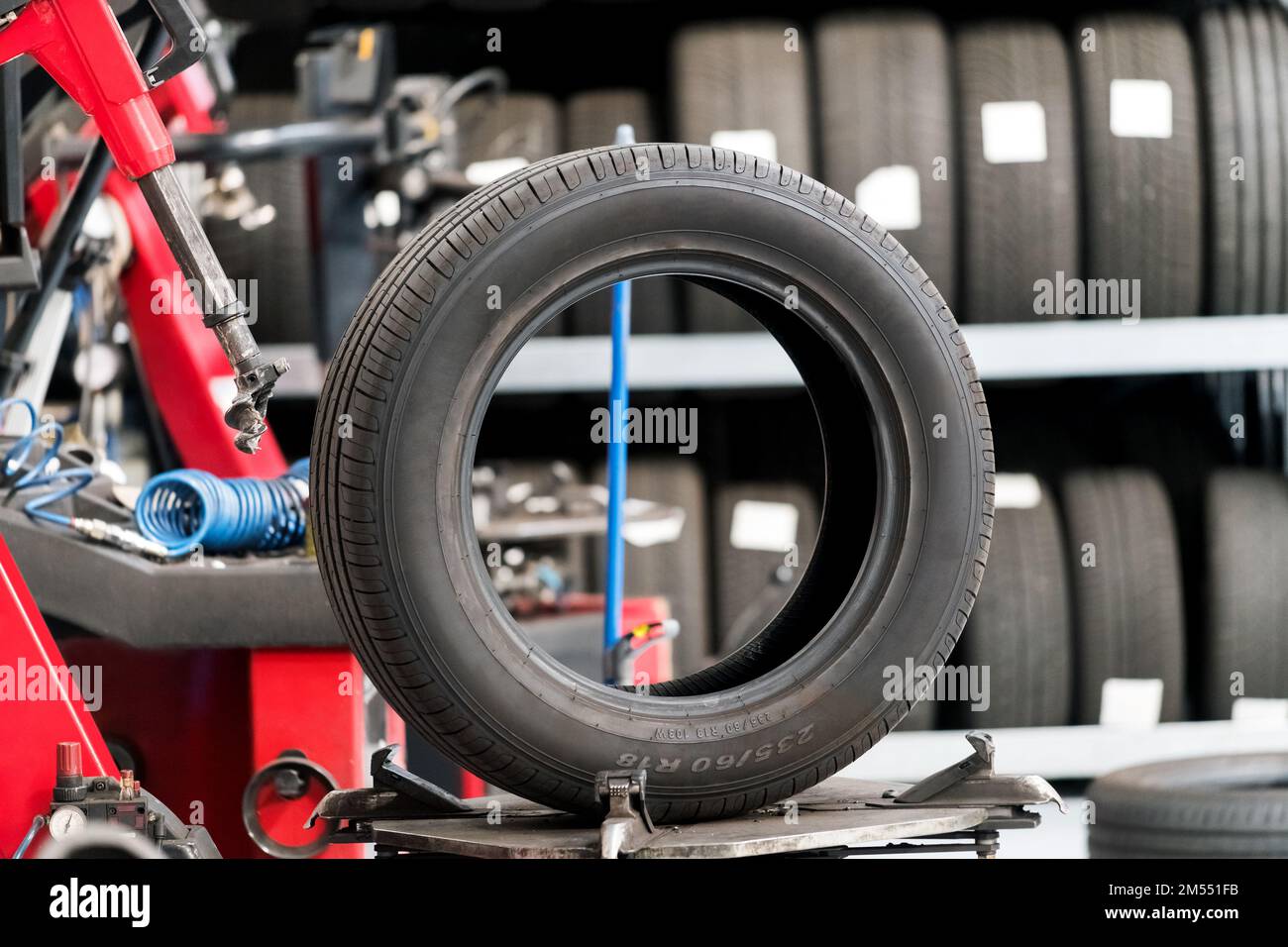 Rubber car tire placed on workbench near machine and shelves in modern workshop Stock Photo