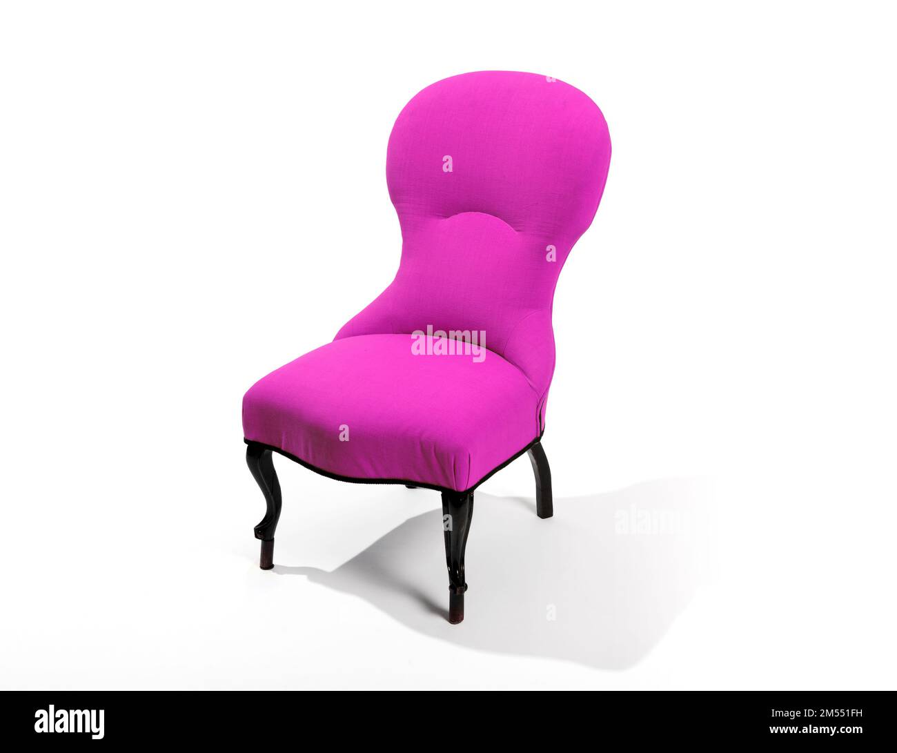Comfortable retro chair with bright fuchsia upholstery and black legs located against white background Stock Photo