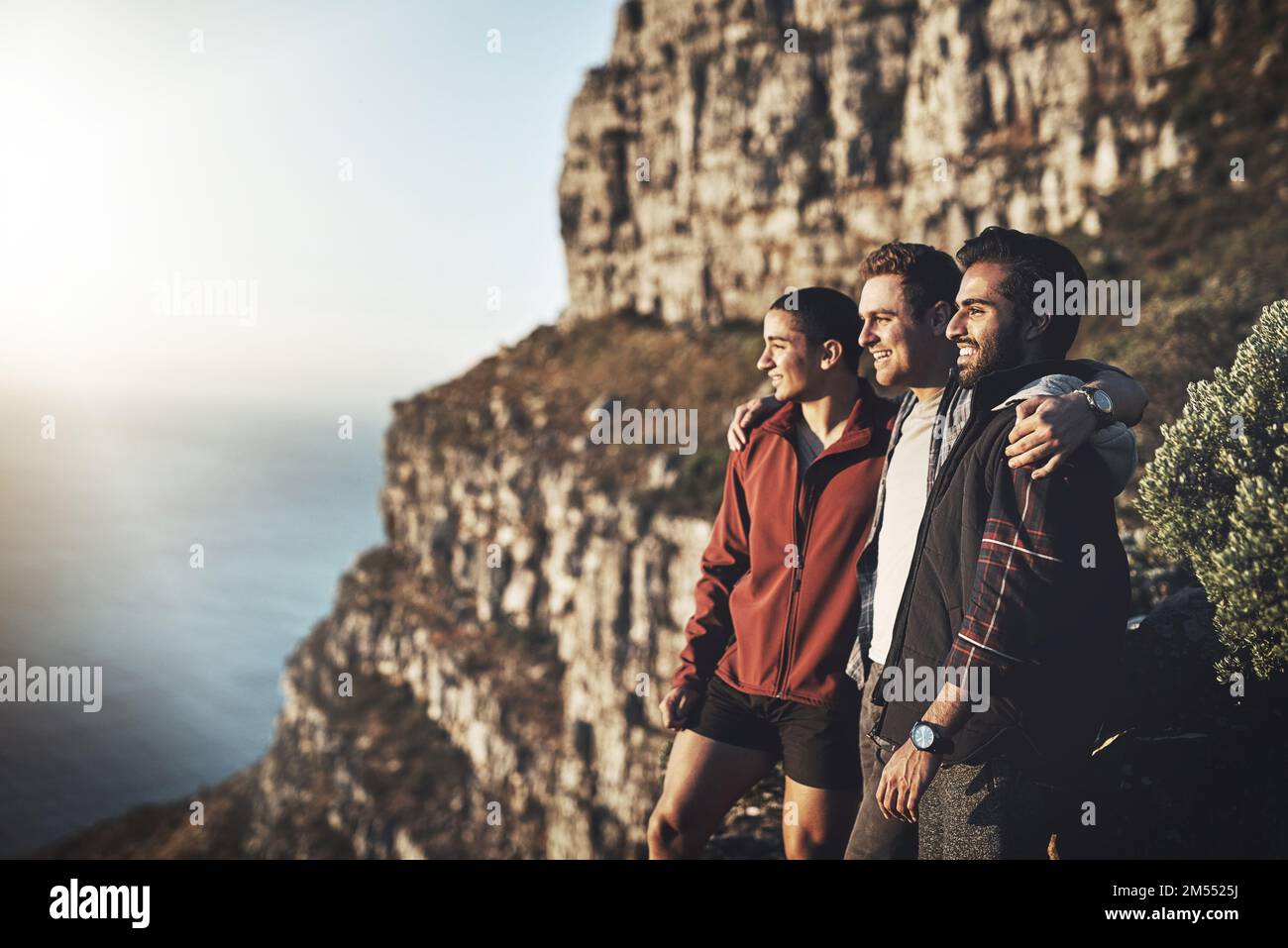 Taking a break on the way to the top. a group of friends admiring the view while hiking in the mountains. Stock Photo