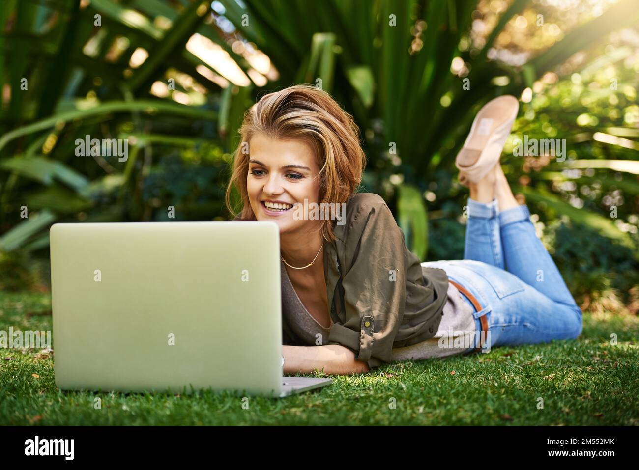 Blogging on the grass. an attractive young woman using her laptop while outside on the grass. Stock Photo