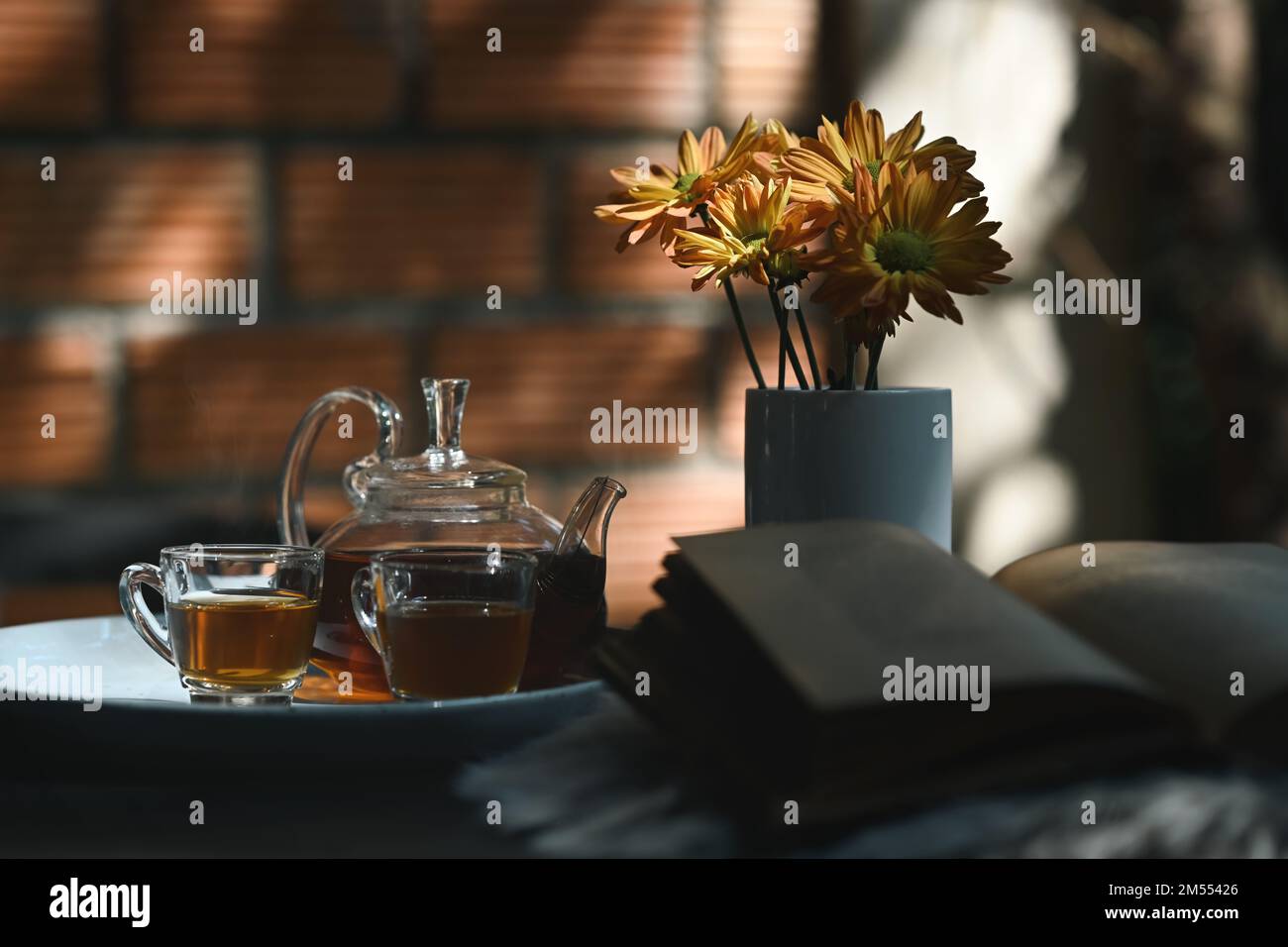 Traditional tea set with cups and teapot, book and flower pot on rustic ...