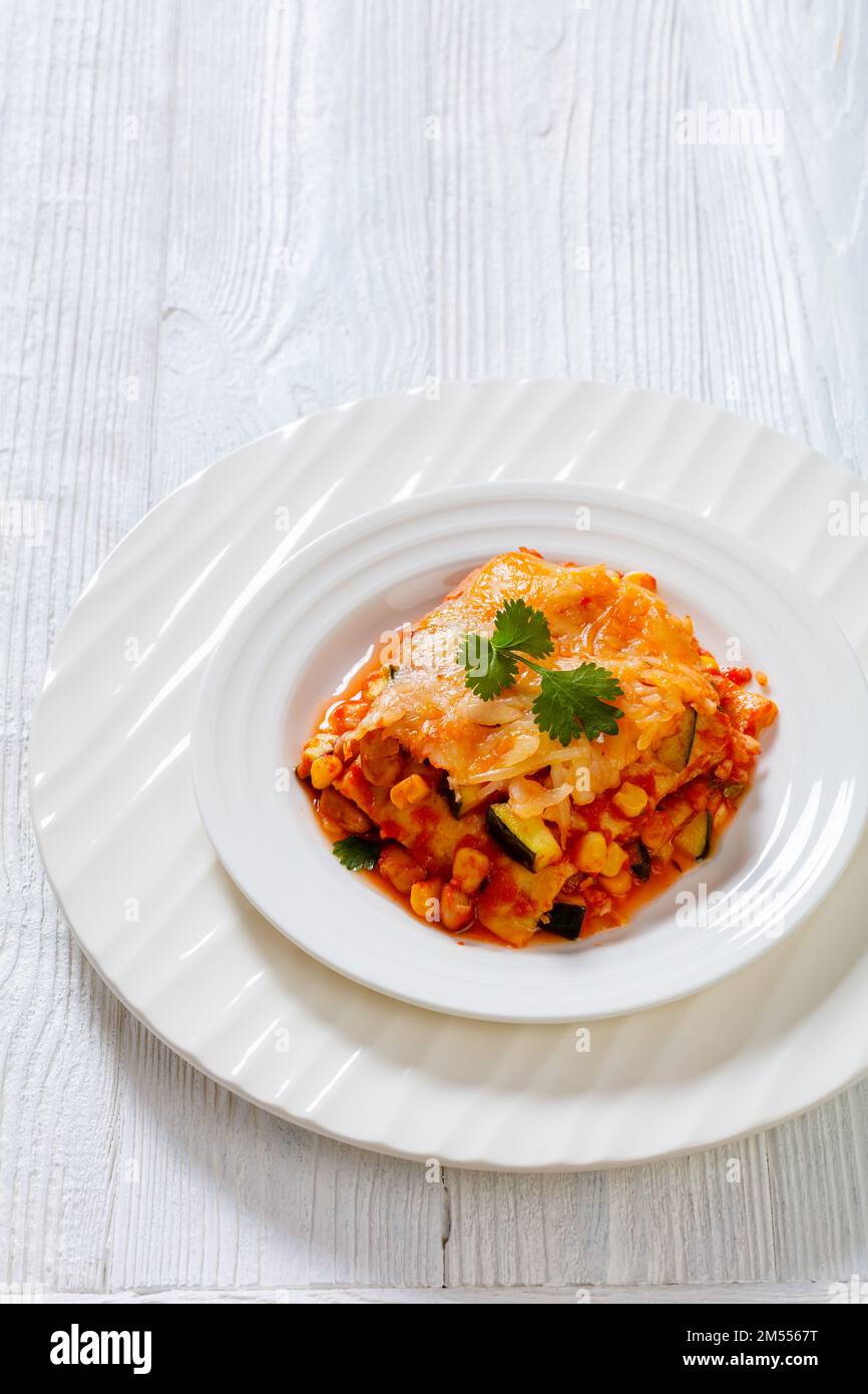 enchilada casserole layered with tortillas, sauce, pinto beans, corn, zucchini and mexican blend