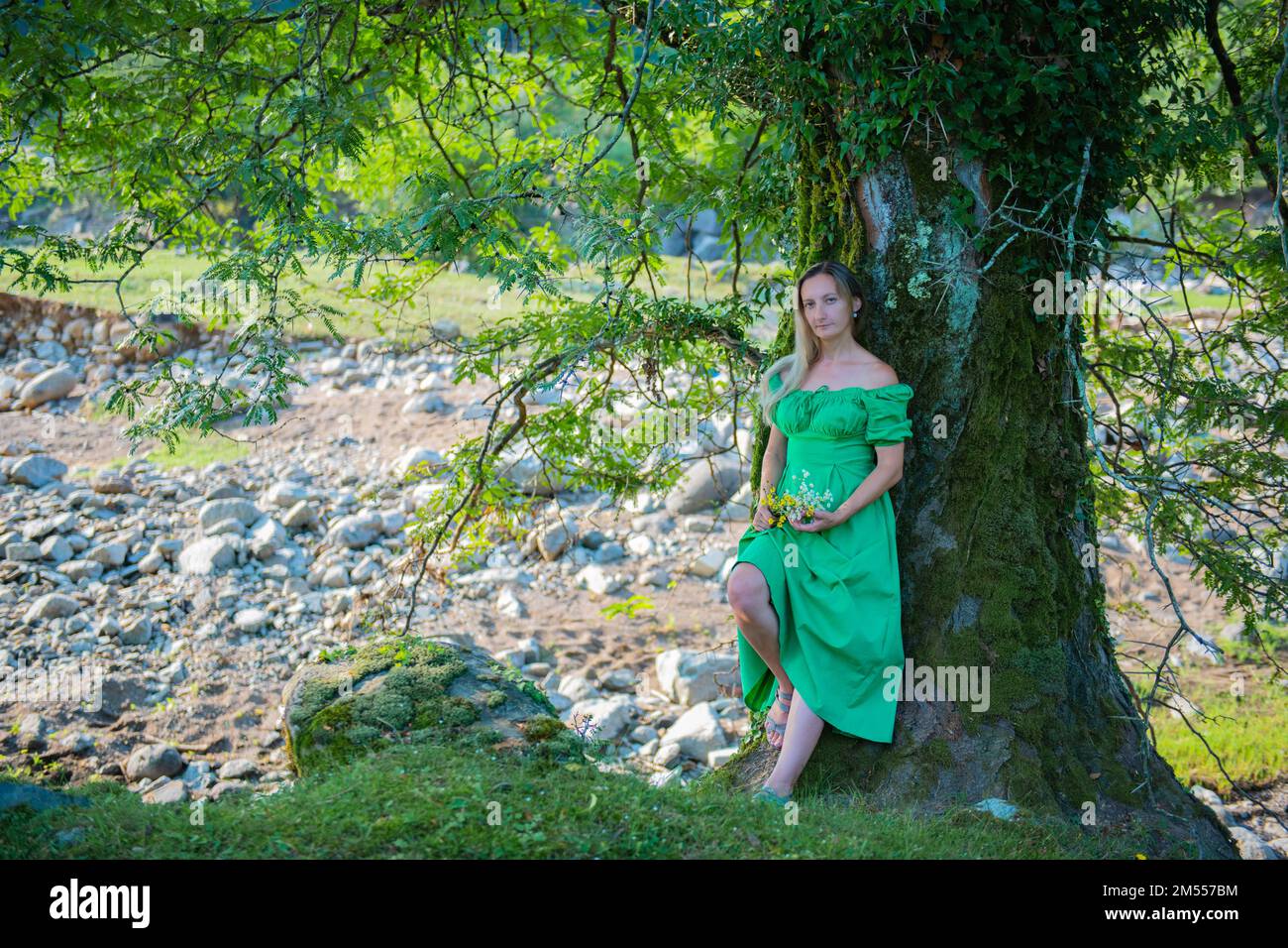 one girl in a green dress is standing by a tree Stock Photo - Alamy