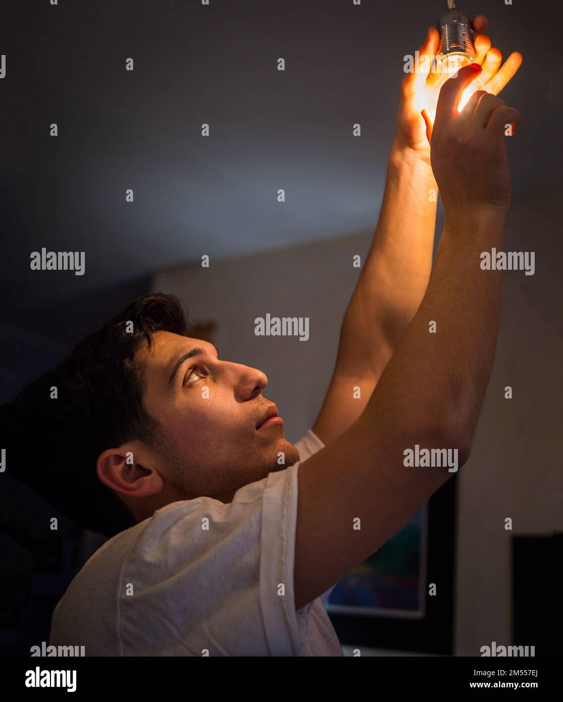 Young man screwing in light bulb at home Stock Photo