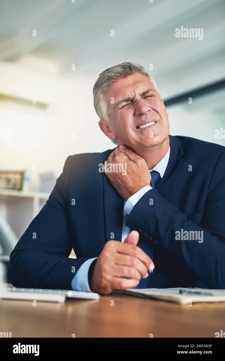 Too many hours in the office chair. a wincing businessman holding his