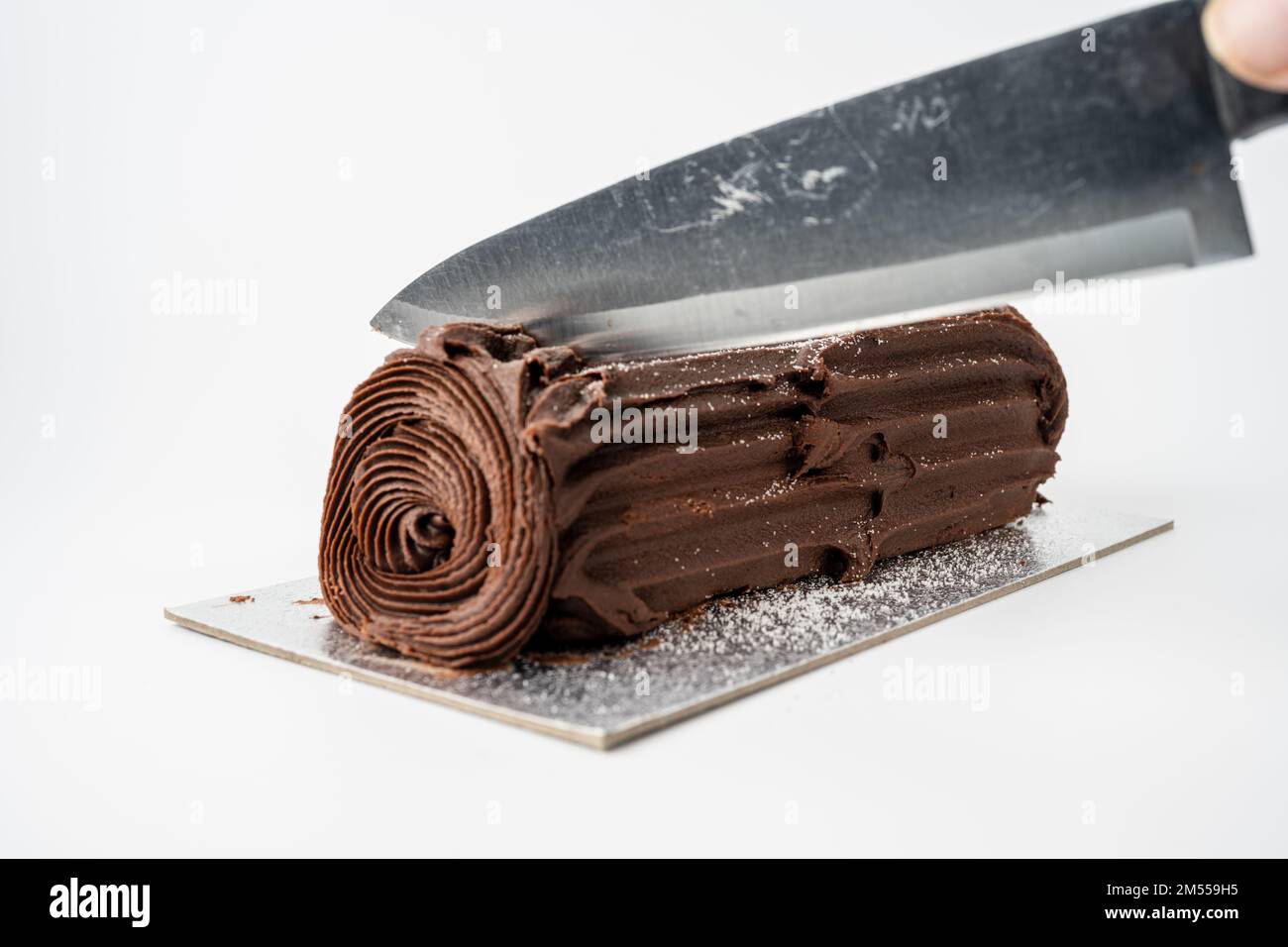 cutting a slice of chocolate christmas log isolated on a white