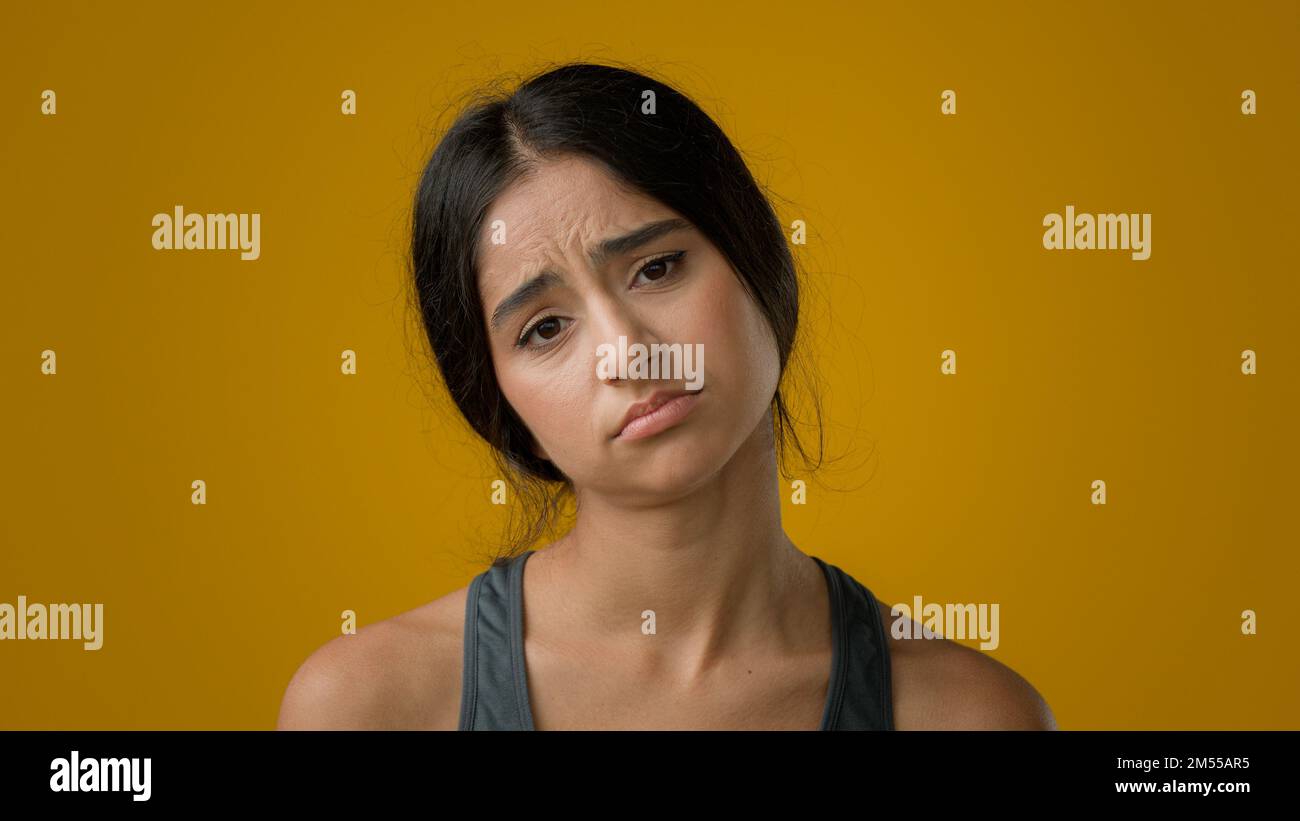 Sad upset worried Indian woman girl in yellow studio background dissatisfied female face with bad body measuring result unhappy weight size shape Stock Photo