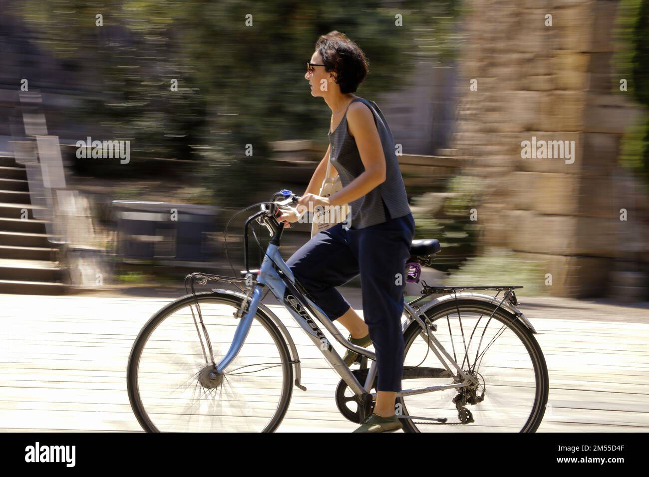 A girl riding a bicycle and going fast on the street in Barcelona ...