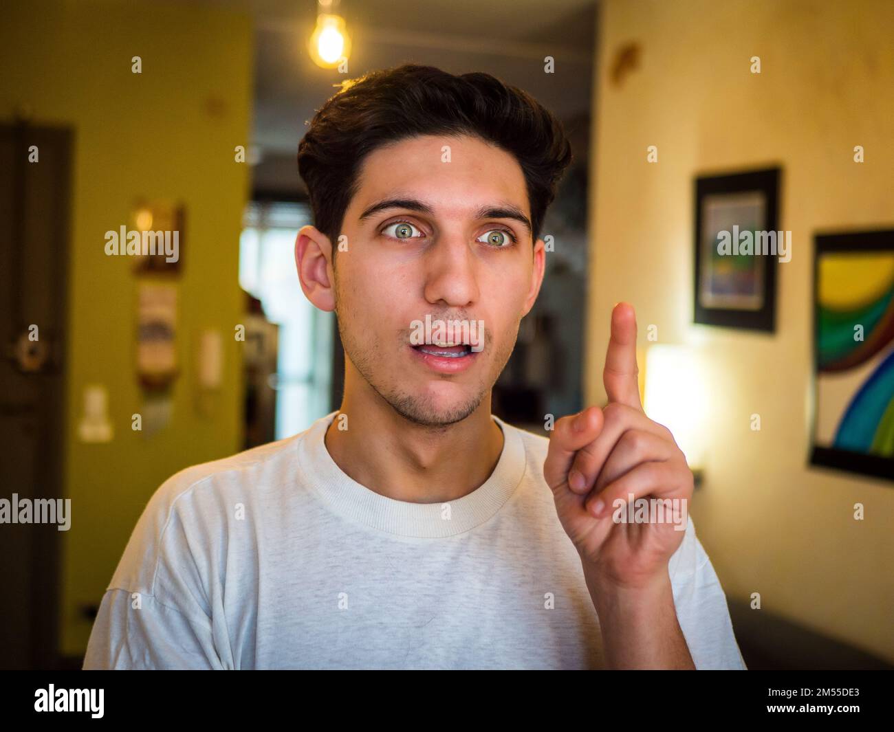 Astonished young man having idea at home Stock Photo