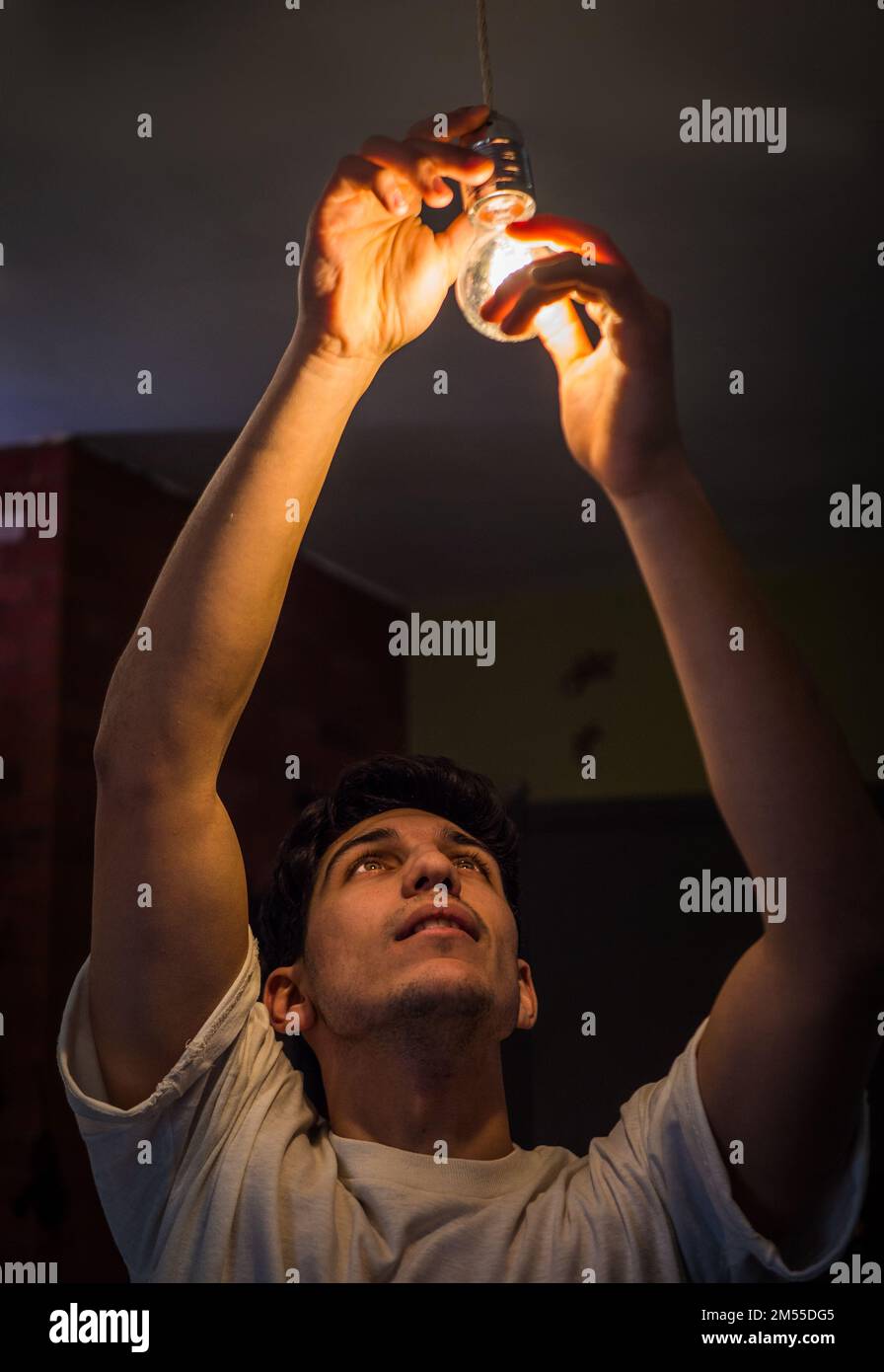 Young man screwing in light bulb at home Stock Photo