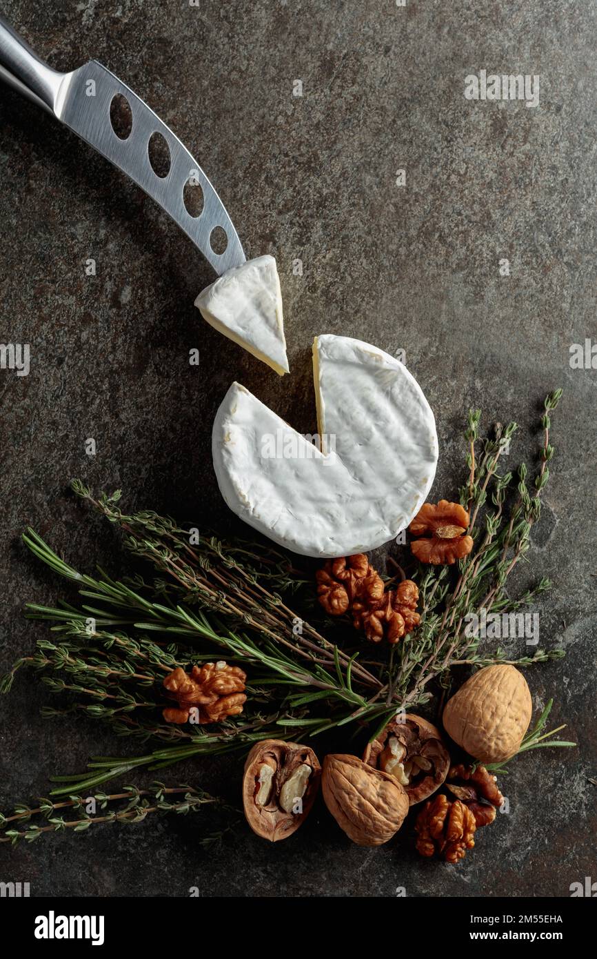 Brie cheese with walnuts, thyme, and rosemary on an old stone