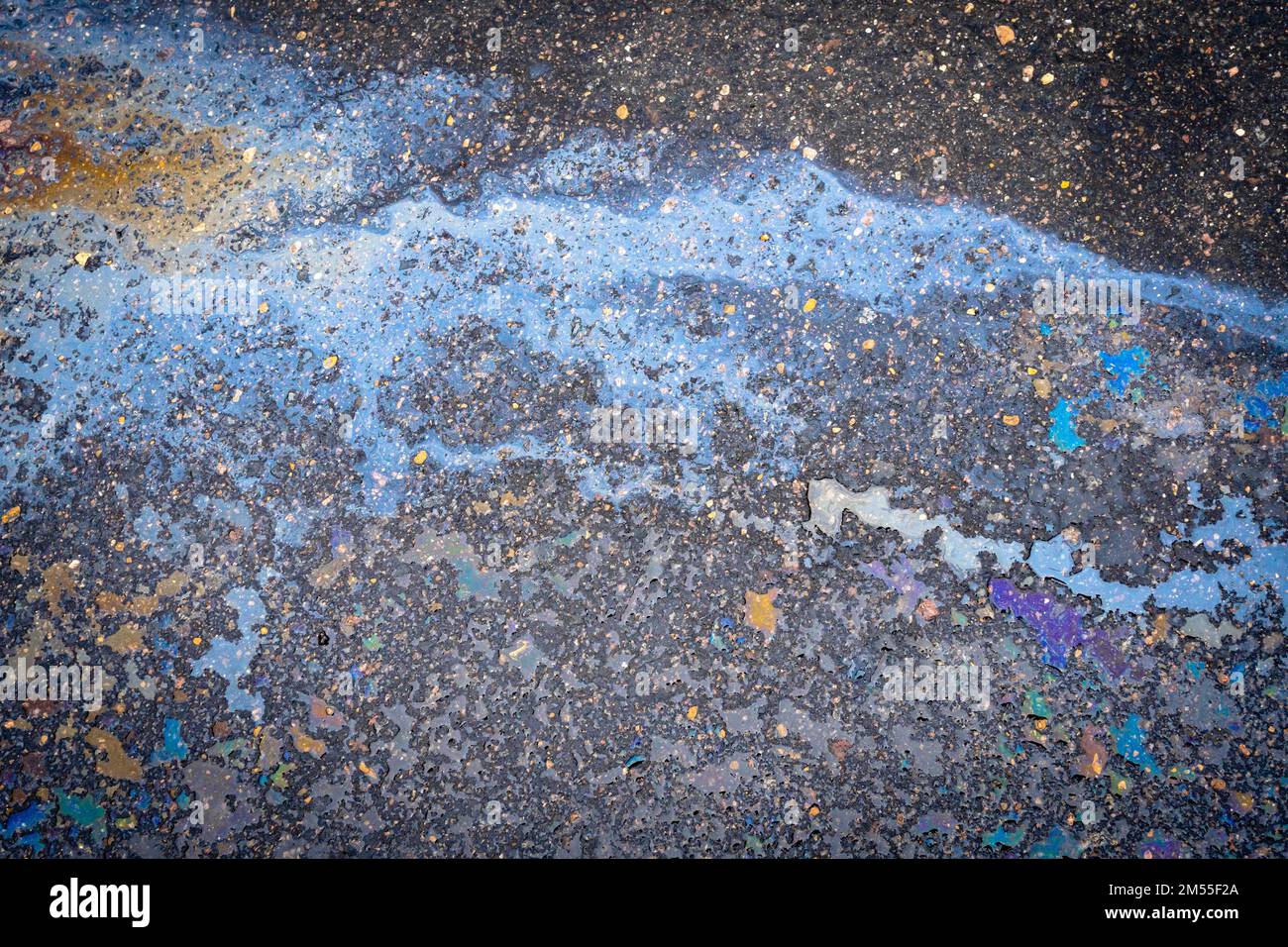 Oil stains from leaks in the car engine. Oil after rain makes spots