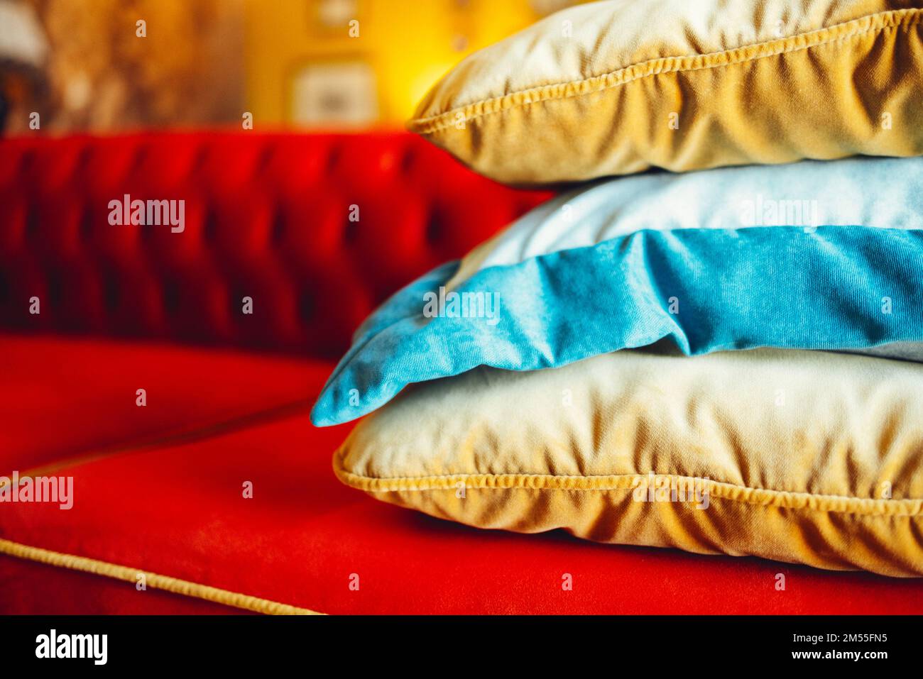 https://c8.alamy.com/comp/2M55FN5/orange-blue-and-beige-pillows-on-a-red-comfortable-sofa-in-a-chic-living-room-interior-close-up-2M55FN5.jpg