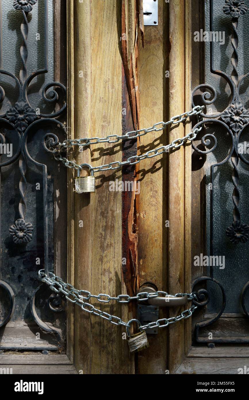 Old wooden door of an abandoned house is locked. Chain on the vintage