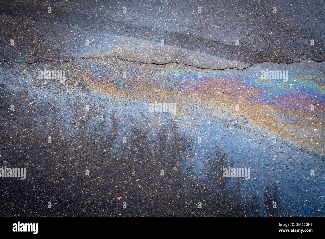 Colorful oil spill on wet asphalt. Oil stains from leaks in the car
