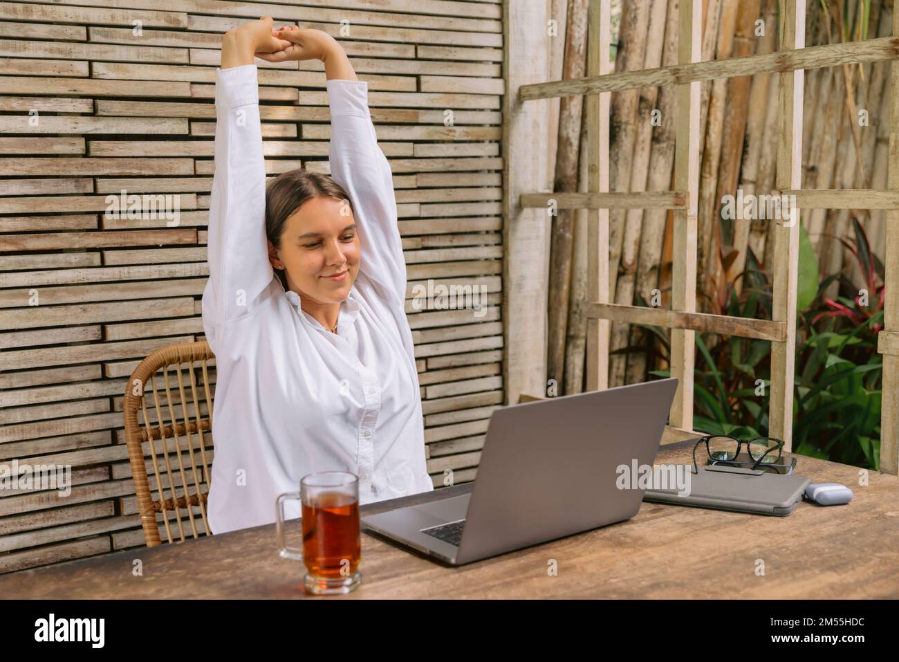 Young happy positive business woman sit indoors in co working using laptop computer. Stock Photo