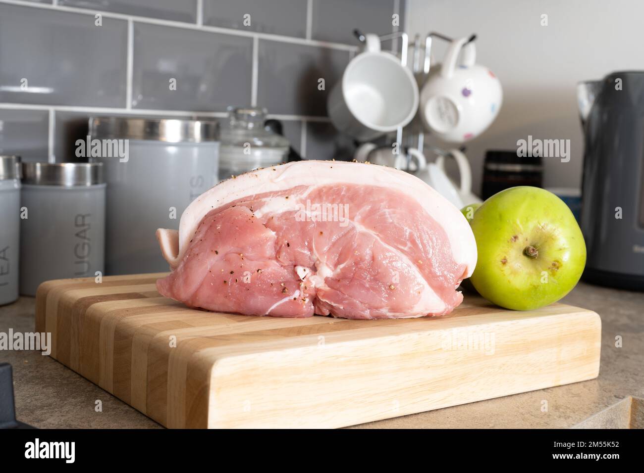 raw uncooked  Pork leg joint with cooking apple on a wooden chopping board Stock Photo