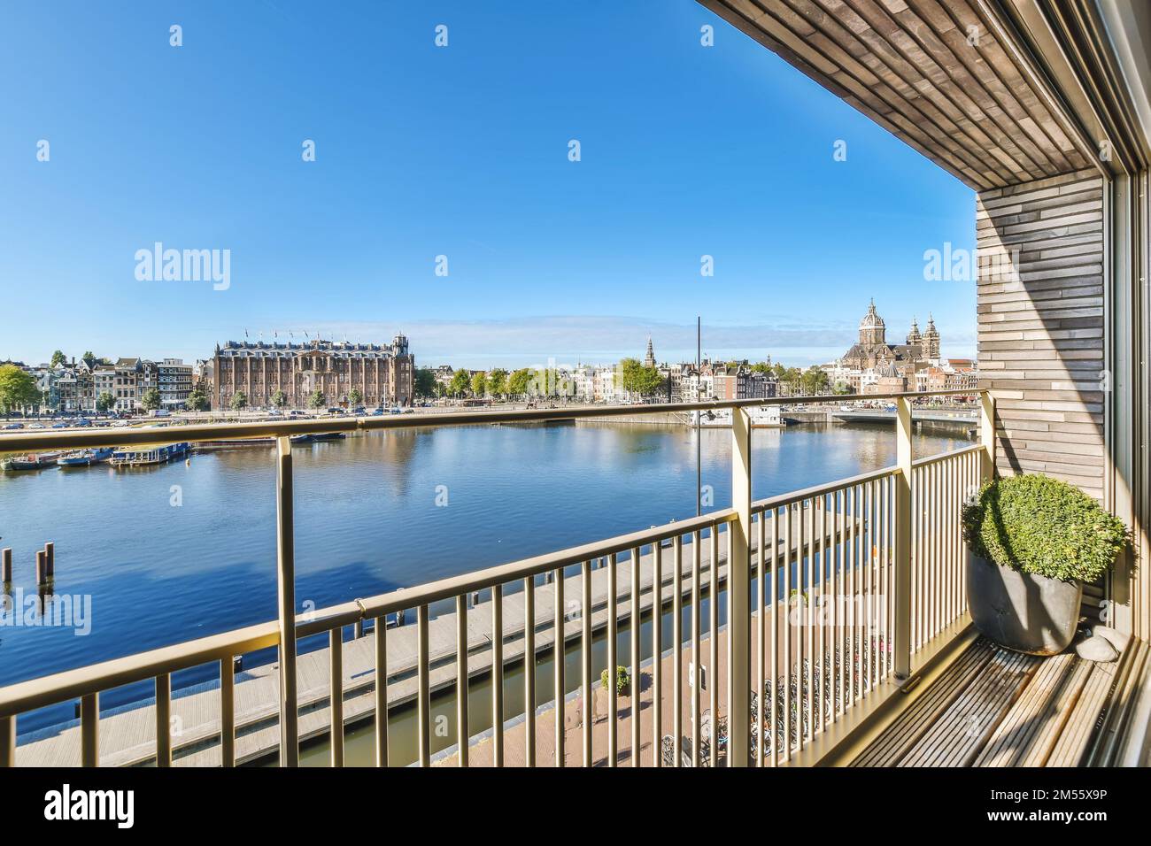 a balcony with a view of the water and buildings in the distance, taken from an apartment window looking out onto the canal Stock Photo