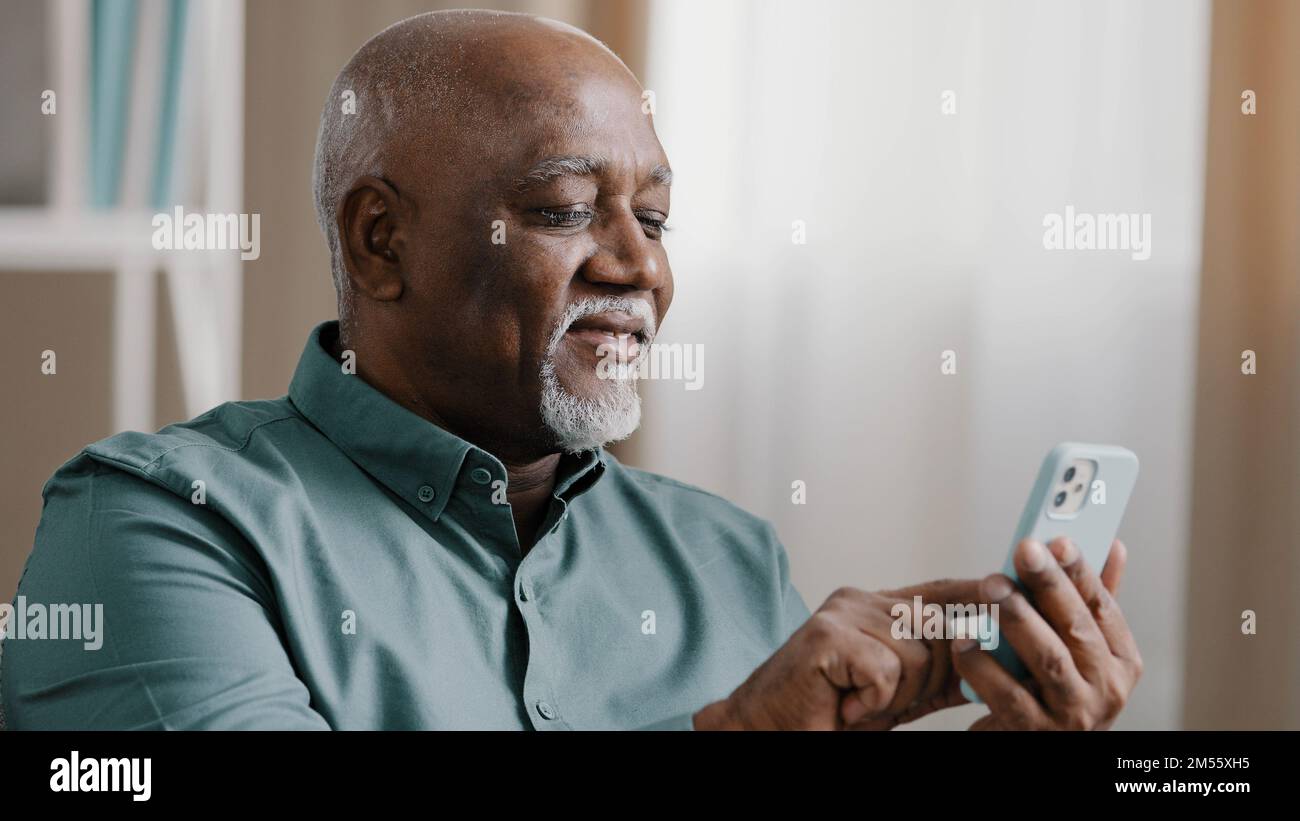 Close up bald American bearded old senior man with gray beard elderly male using software application net on cellphone reading message email swiping Stock Photo