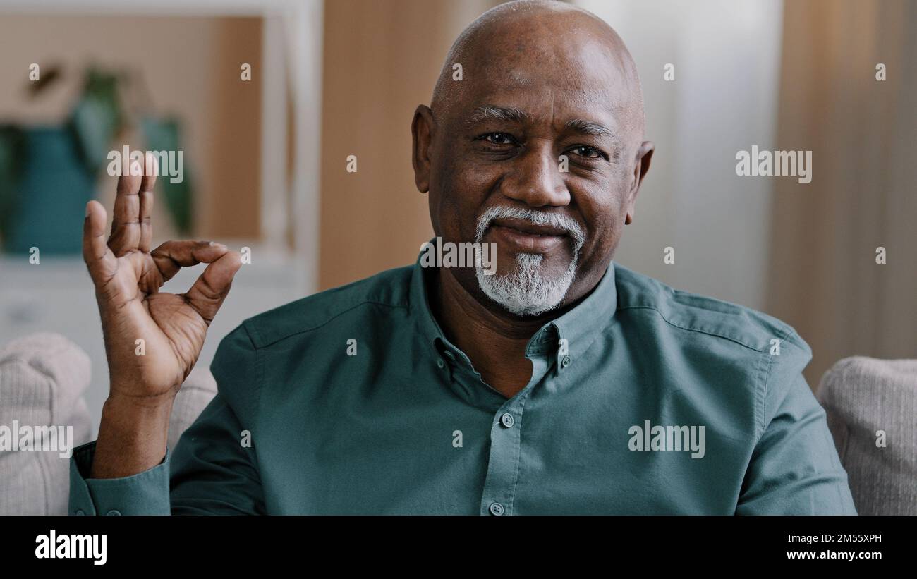 Close up smiling african american mature man portrait pleased pensioner male sitting in apartment happy wrinkled face elderly retiree grandfather Stock Photo
