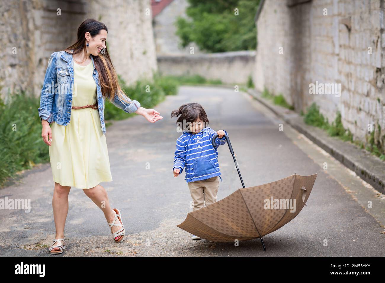 Mother and little handsome baby boy playing with umbrella outdoor in old town Stock Photo