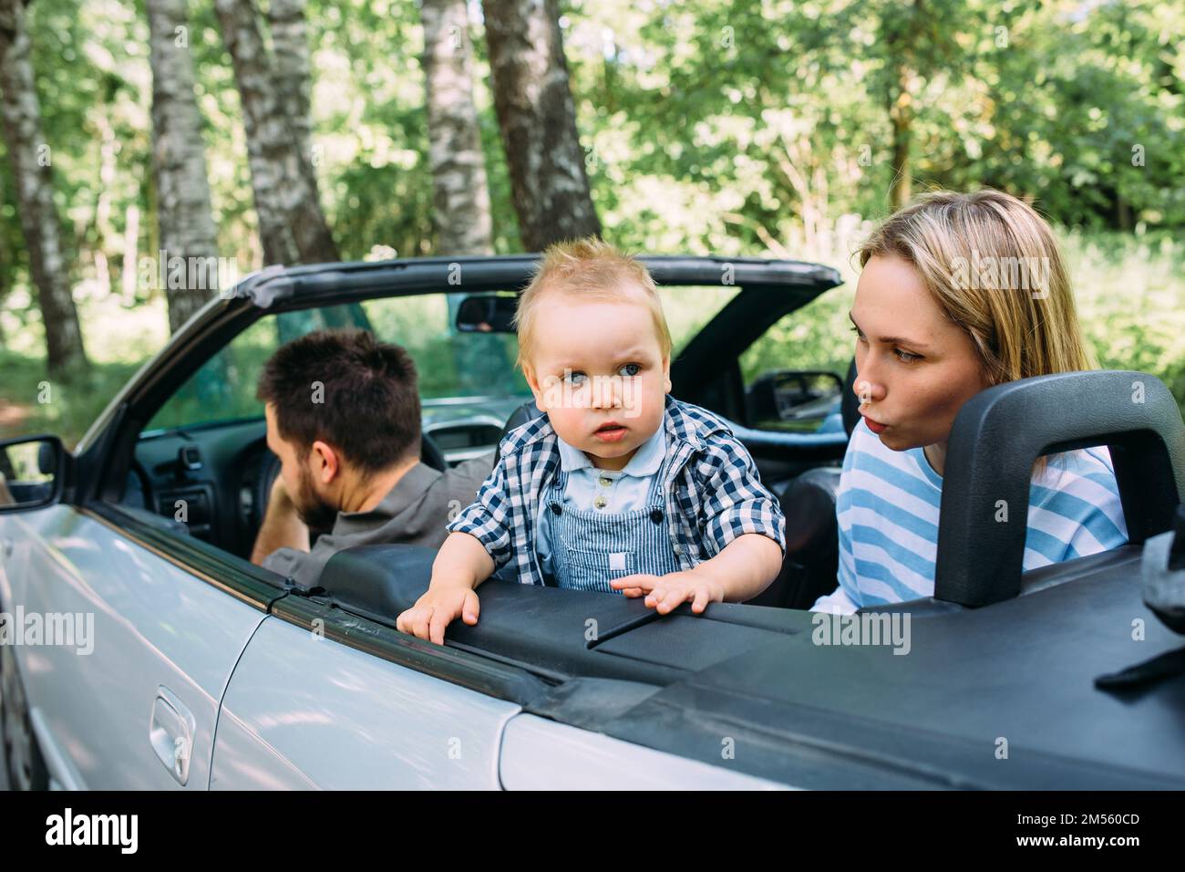 Mom, dad and little son in a convertible car. Summer family road trip ...