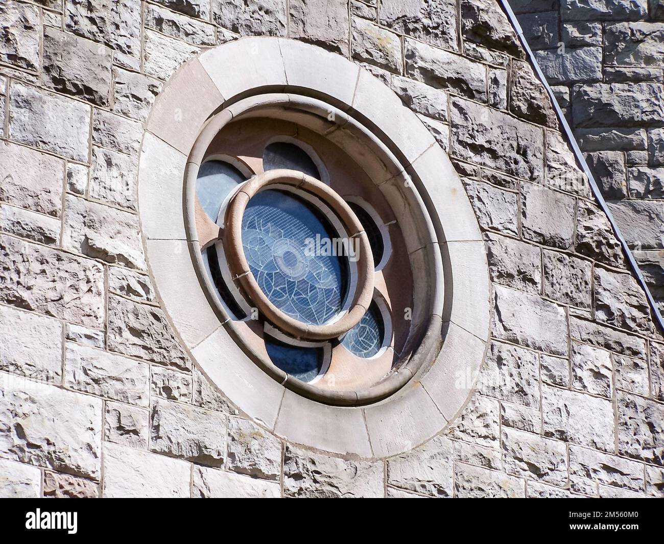 Stained glass rose window in a stone wall of a 19th century Irish