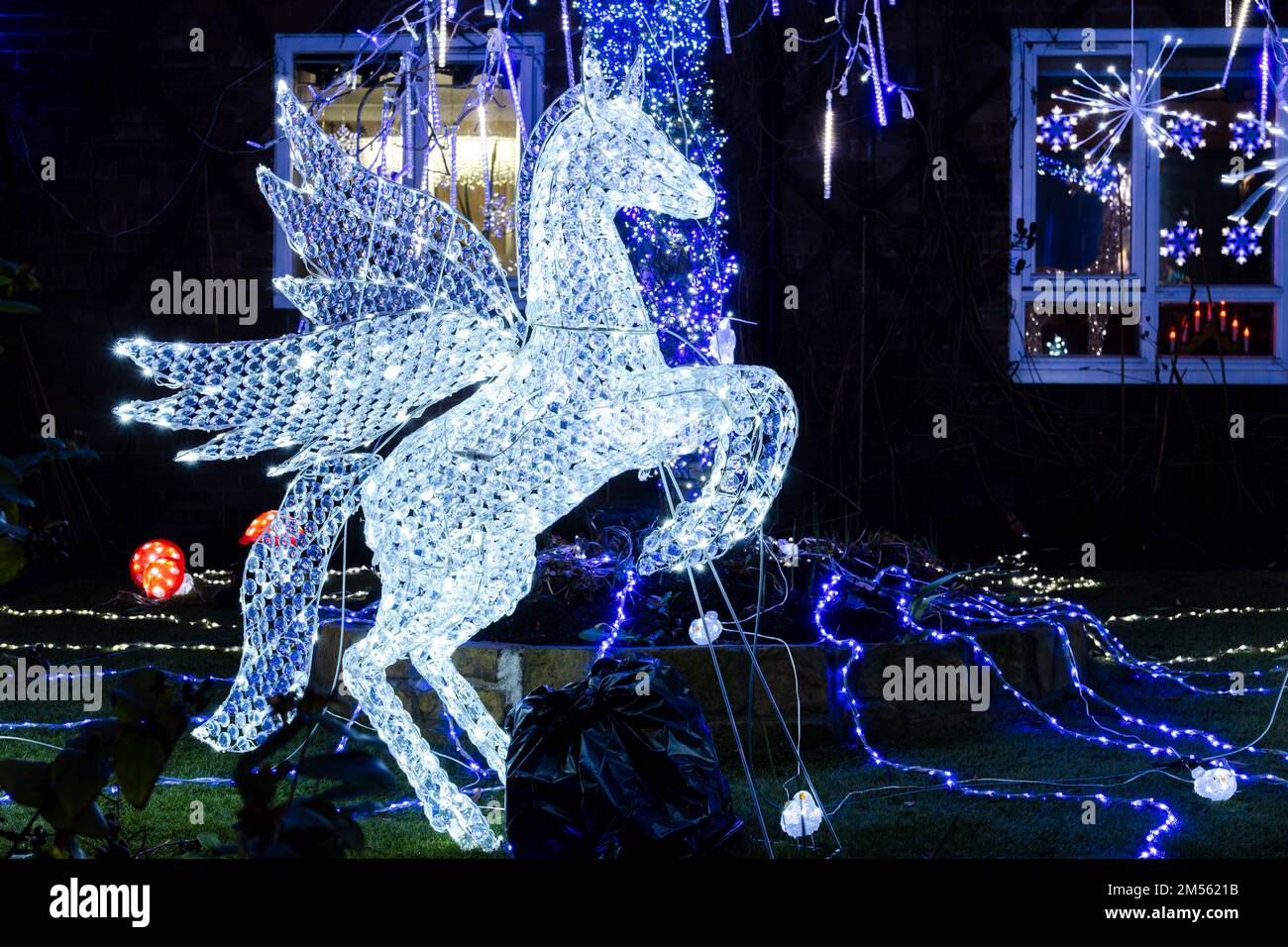 A glowing white Pegasus among Christmas decorations outside of an apartment building in the UK at night. Stock Photo