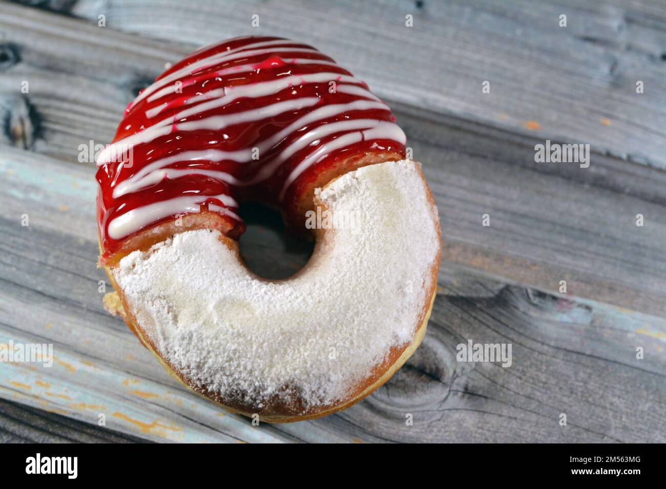 Icing powdered confectioners' sugar and Strawberry flavored ring donut, A glazed, yeast raised, American style ring doughnut with topping, type of foo Stock Photo